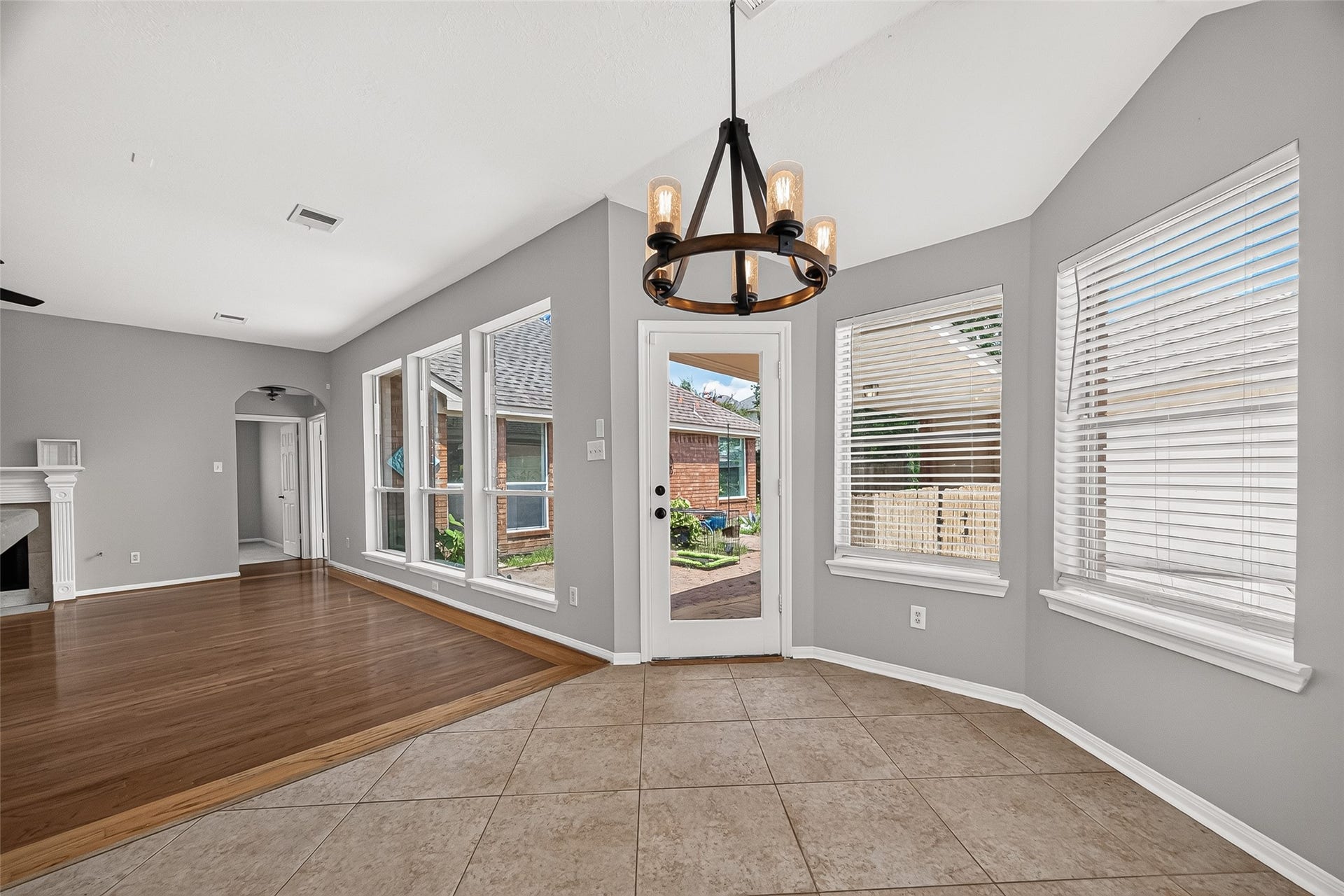 12823 Lady Jane Court, Houston, TX 77044 Bright dining area with large windows, stylish chandelier, and easy access to the outdoor space, seamlessly connecting to a spacious living room with elegant wood flooring and a cozy fireplace.