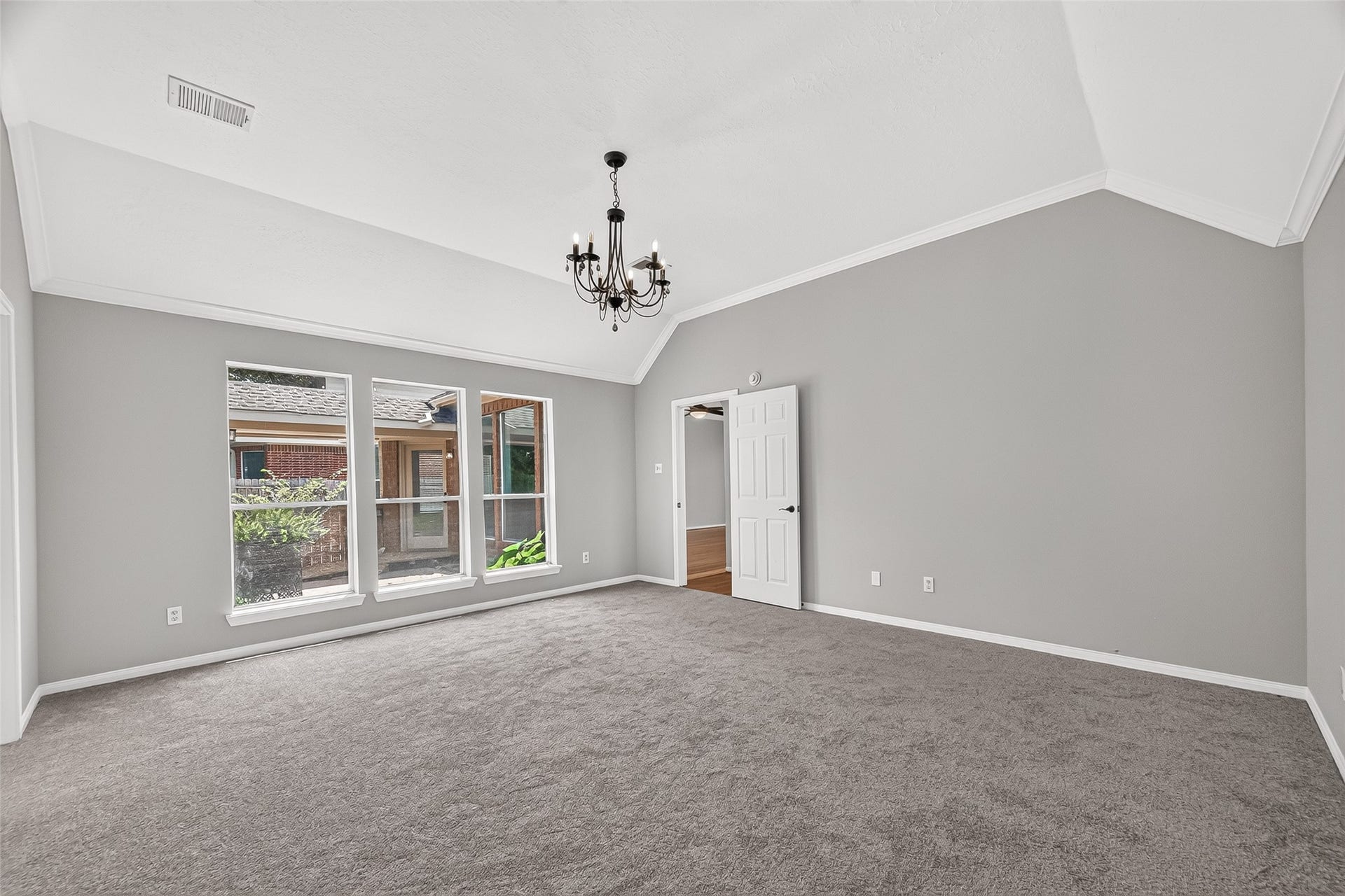 12823 Lady Jane Court, Houston, TX 77044 Spacious, light-filled room with elegant tray ceiling, plush carpeting, and a charming chandelier, offering a versatile space for relaxation or entertainment.