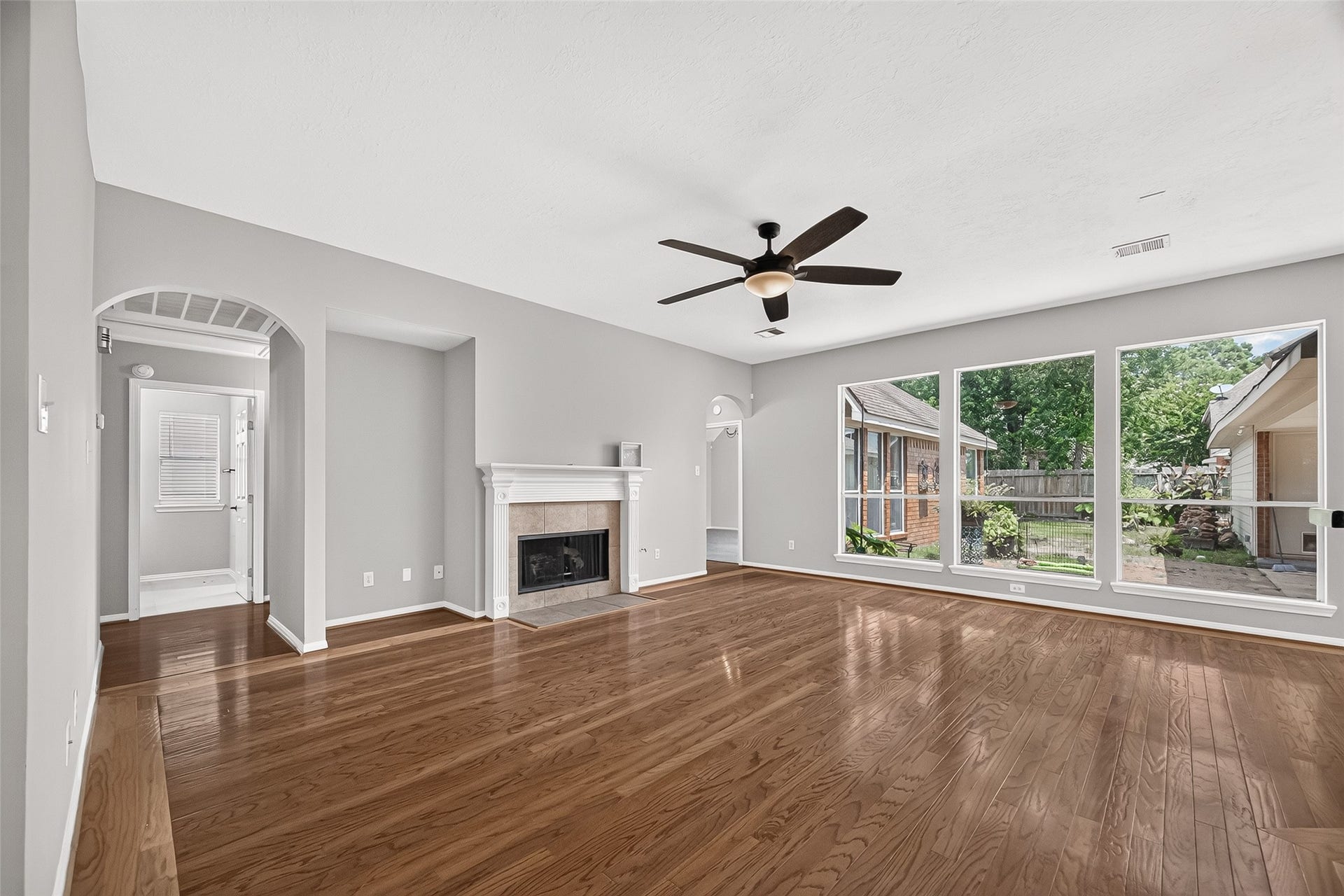 12823 Lady Jane Court, Houston, TX 77044 Spacious living room featuring elegant hardwood floors, a cozy fireplace, and large windows with views of the backyard, creating a bright and inviting atmosphere.