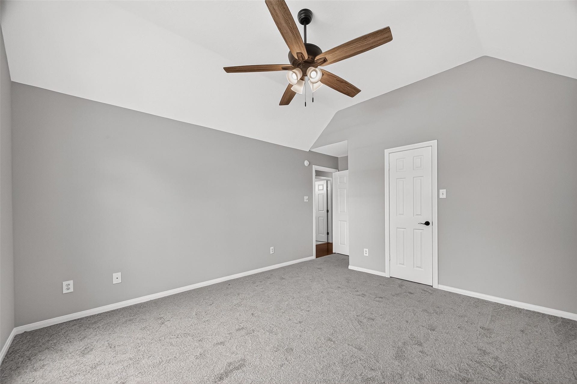12823 Lady Jane Court, Houston, TX 77044 Spacious bedroom with soft gray walls, plush carpeting, and a stylish ceiling fan, offering a tranquil retreat.