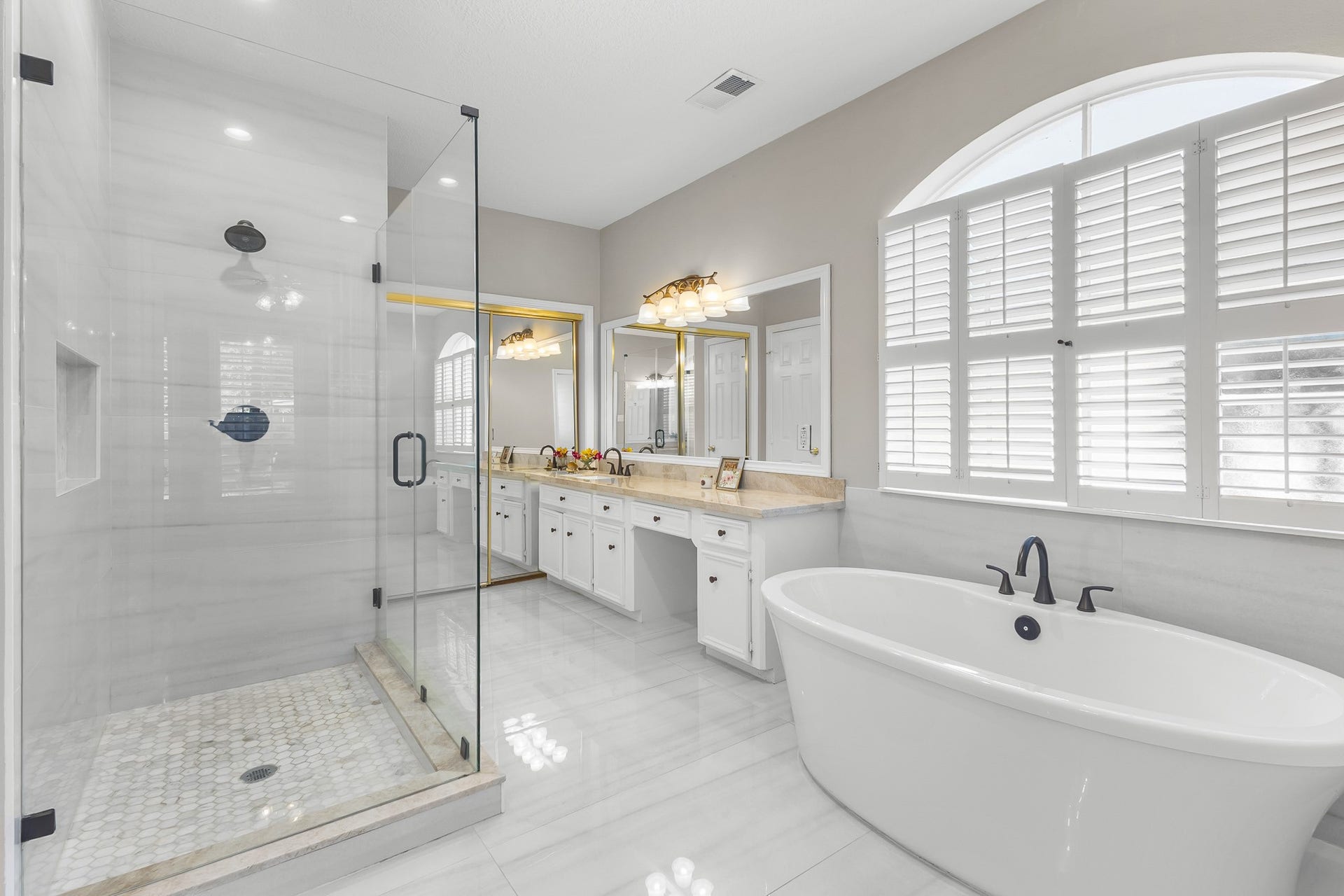 16314 Graven Hill Drive, Spring, TX 77379 A well-appointed primary bath features a soaking tub, glass-enclosed shower, dual vanities and an expansive arched window.