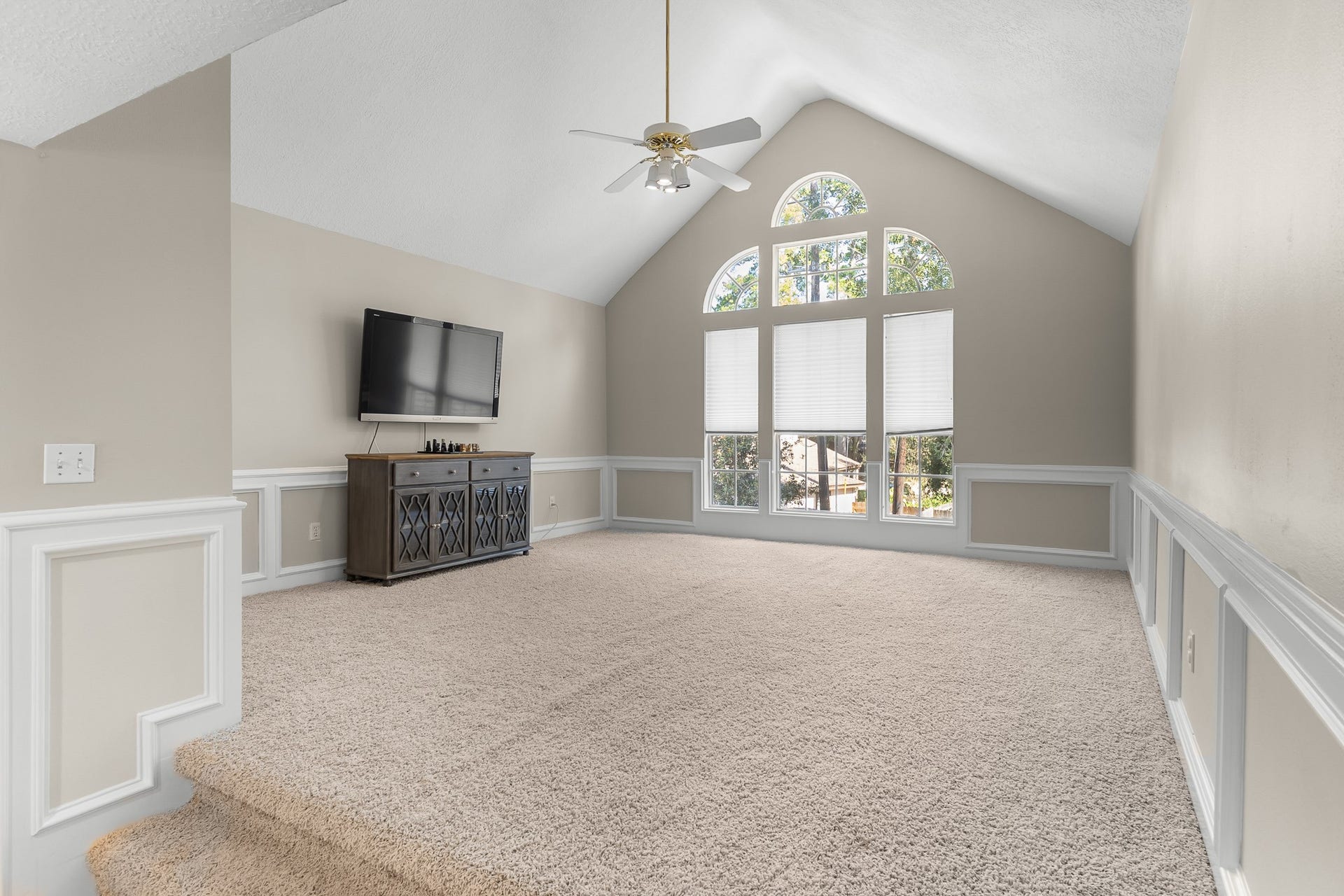 16314 Graven Hill Drive, Spring, TX 77379 An expansive game room features a vaulted ceiling, decorative wall paneling and a dramatic arched window, offering space for recreation and relaxation.