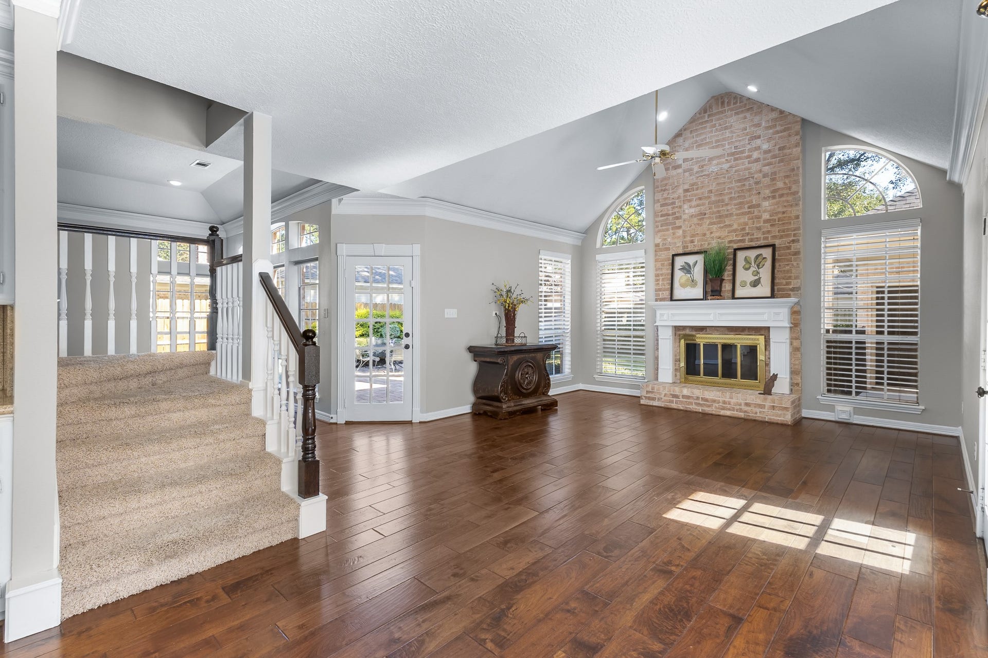16314 Graven Hill Drive, Spring, TX 77379 A dramatic brick fireplace rises between expansive windows, anchoring the family room beneath its vaulted ceiling.