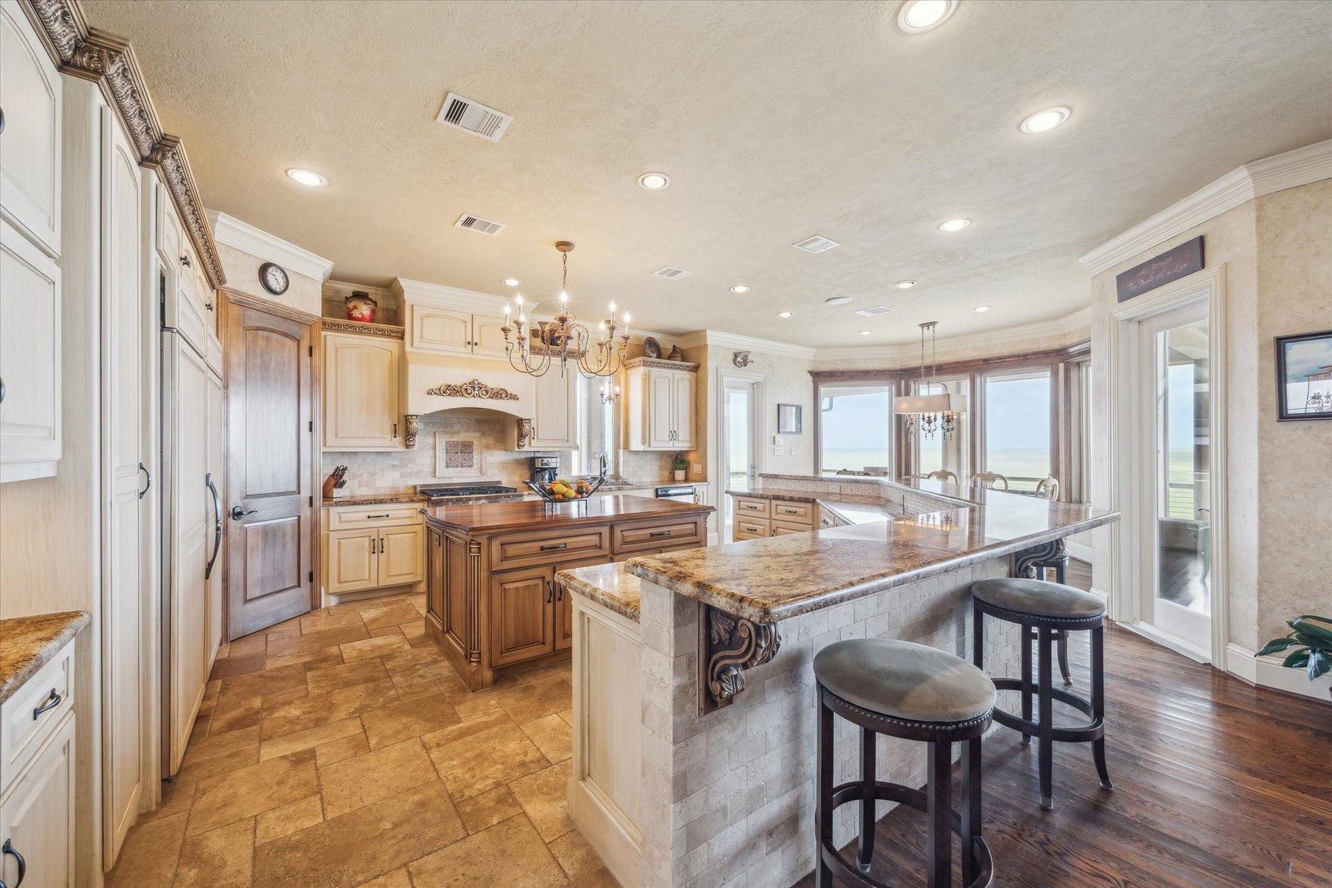 9 Happy Jack, Hitchcock, TX 77563 The beautiful kitchen features a large central island, rich wood cabinetry, and warm granite countertops. High-end appliances. Ornate details, custom cabinetry, and expansive bayfront windows complete the timeless Mediterranean design