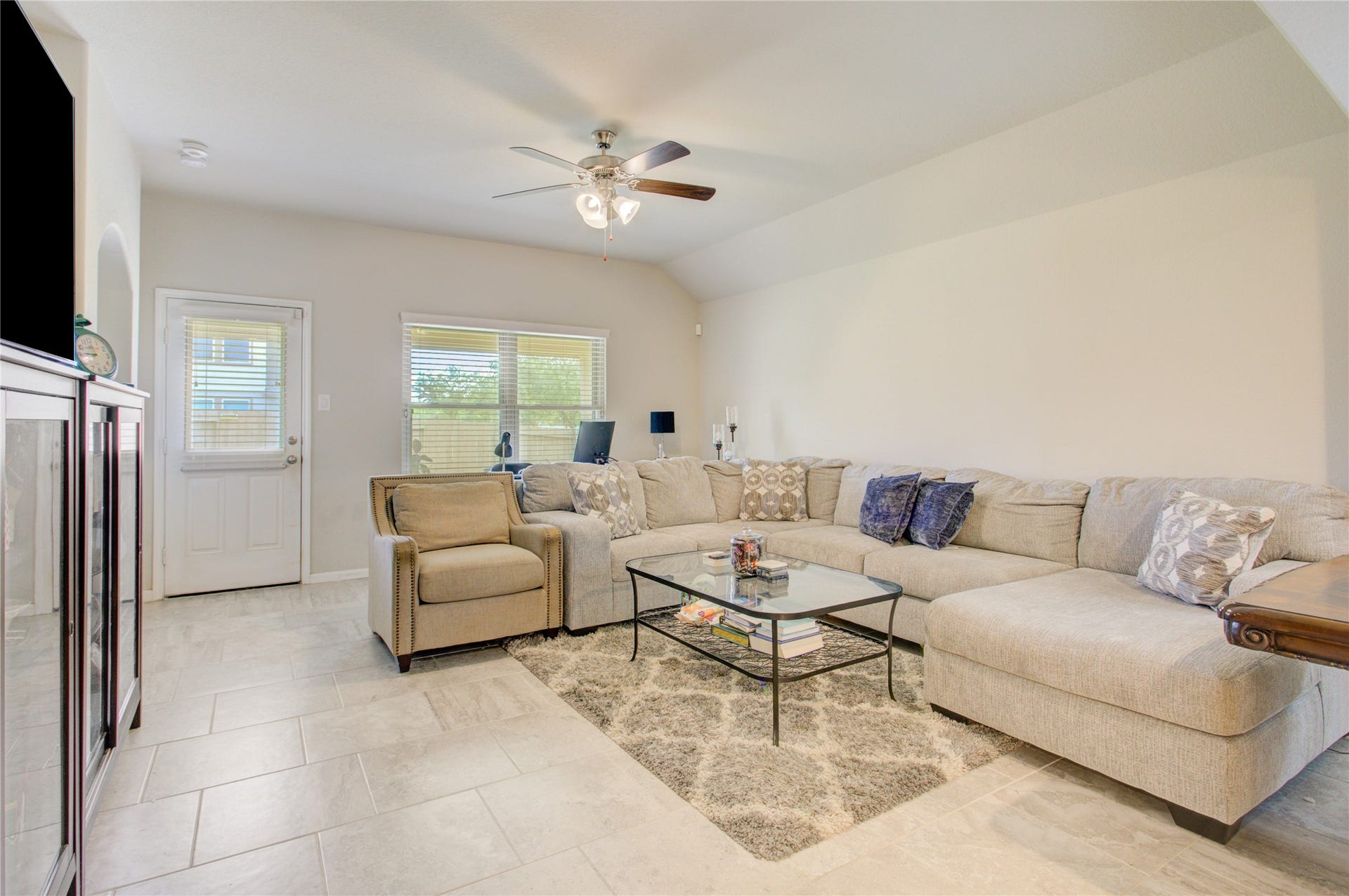 Unwind in the inviting living room featuring vaulted ceilings, abundant natural light, and beautiful tile flooring.