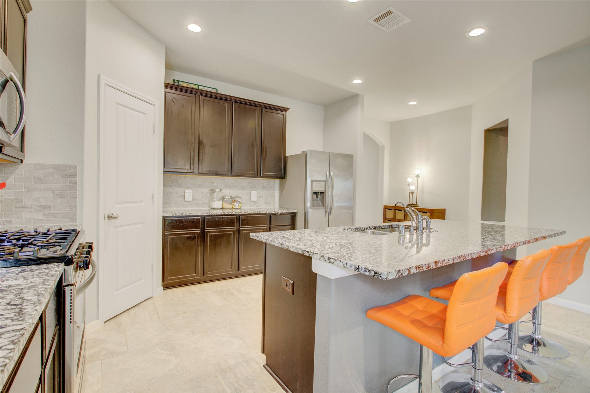 A chef-inspired kitchen featuring a five-burner gas range, tile backsplash, ample cabinetry, and stainless steel appliances.