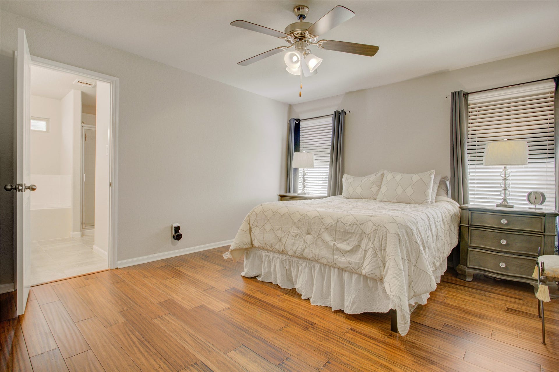 Retreat to your spacious primary suite featuring beautiful wood flooring, abundant natural light, and a private ensuite bath. Enjoy a peaceful primary retreat with generous space for furnishings, two windows, and the warmth of wood flooring throughout.