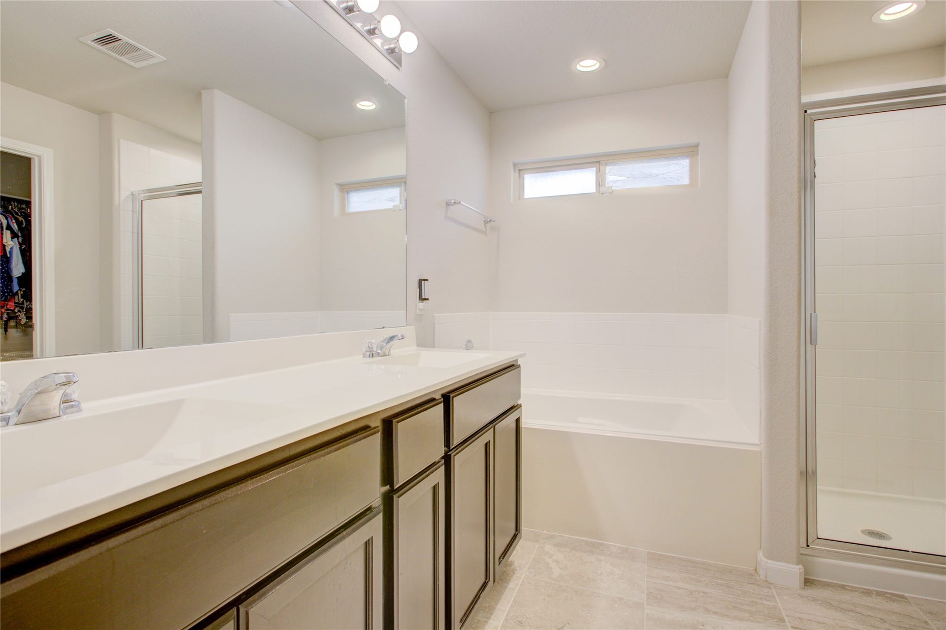 Unwind in your private ensuite featuring dual sinks, a relaxing soaking tub, separate glass-enclosed shower, and spacious vanity.