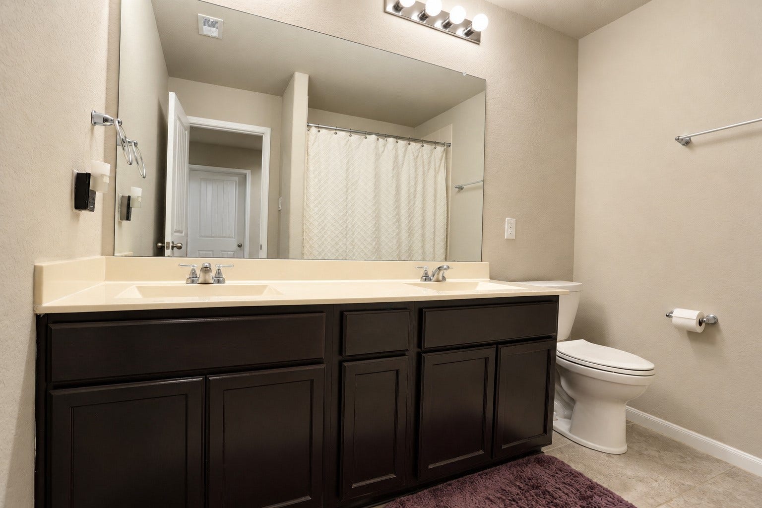 Conveniently designed bathroom featuring dual sinks, generous counter space, and cabinetry for additional storage.