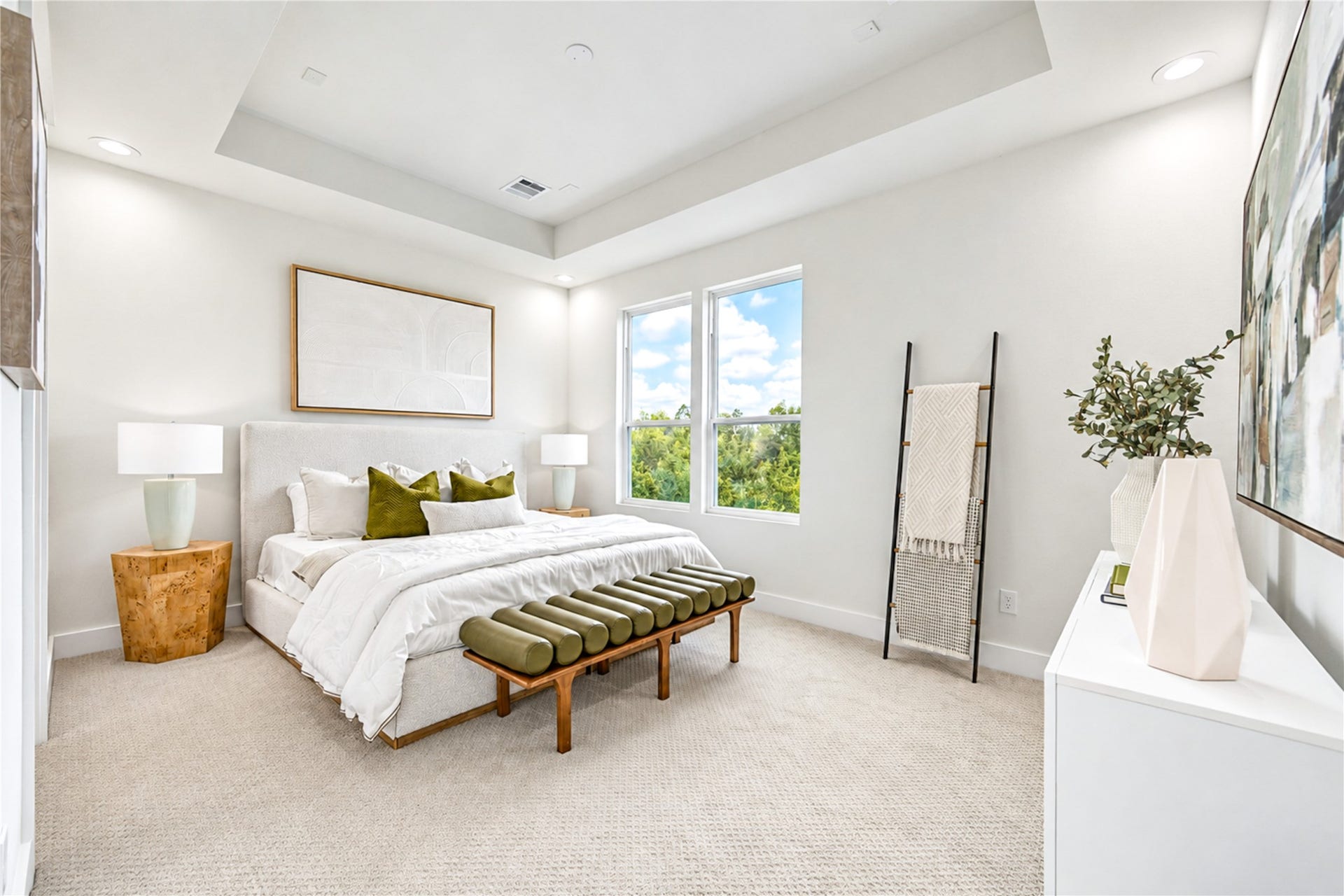 Bright and airy primary suite featuring an elegant tray ceiling, neutral palette, and large windows.