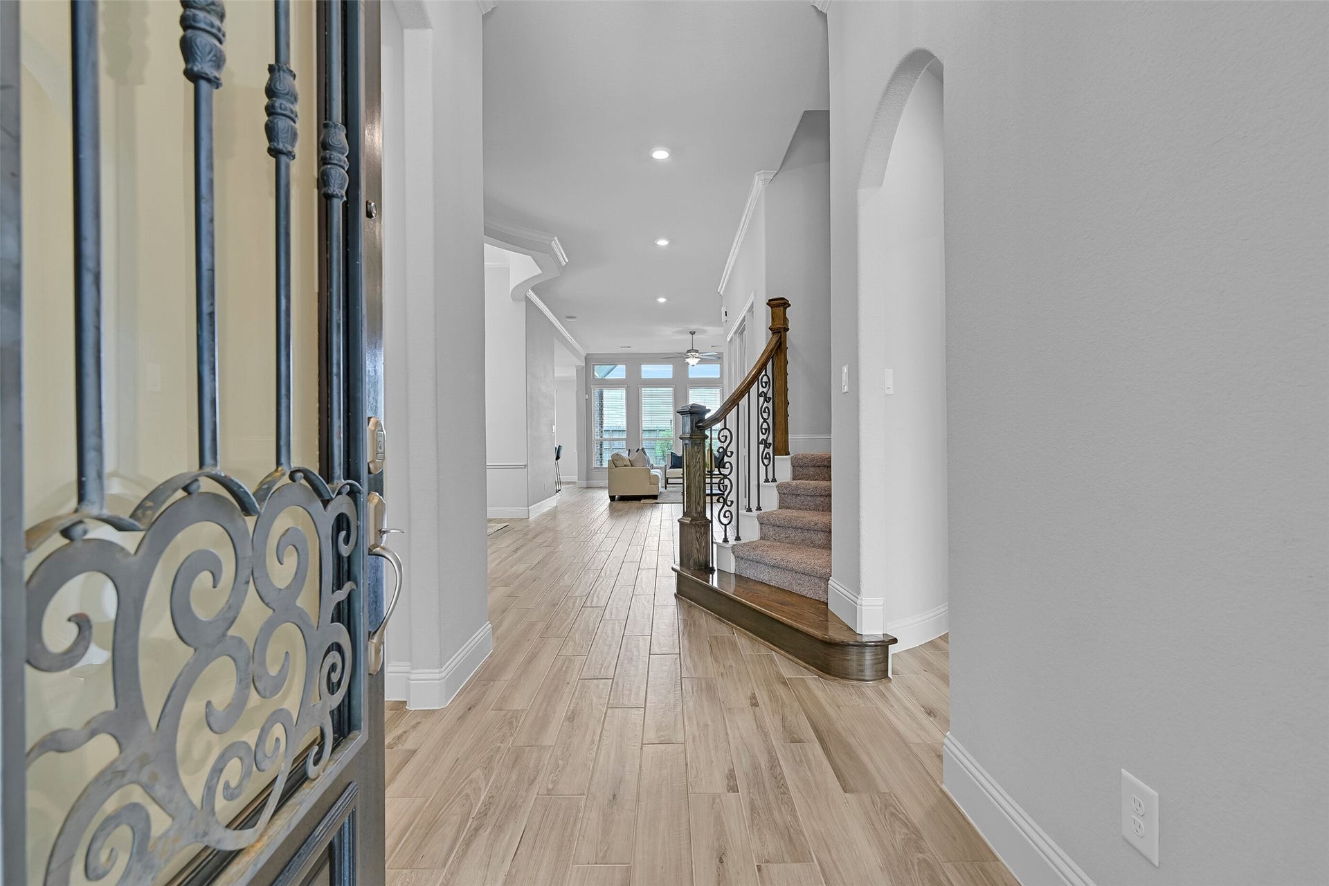 1321 Summer Field Lane, Friendswood, TX 77546 Step inside to a grand foyer featuring wood-look tile flooring, fresh interior paint, crown molding, inset art niches, and a striking split staircase with wood and iron handrails. The open sightline straight through to the family room immediately showcases the home's spacious design.