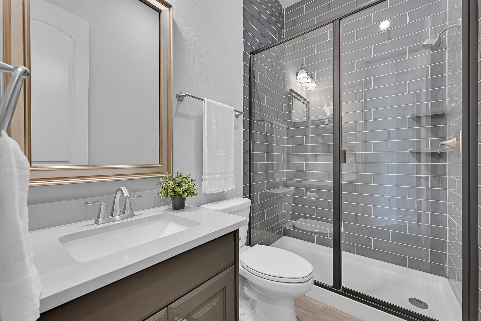 1321 Summer Field Lane, Friendswood, TX 77546 Conveniently located just outside the bedroom and near the front foyer, this full bath features an upgraded vanity with quartz countertop, framed mirror, and a beautifully tiled walk-in shower with sleek glass enclosure. The designer finishes make it perfect for guests while maintaining privacy from the home's main living spaces.