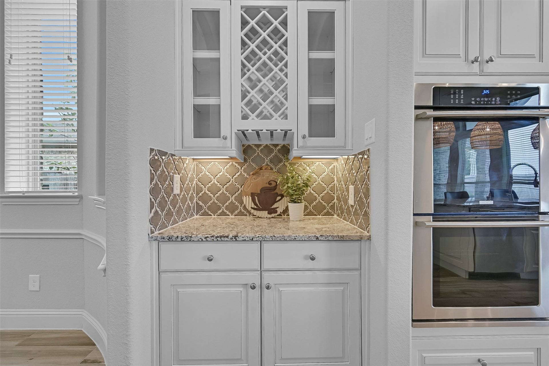 1321 Summer Field Lane, Friendswood, TX 77546 Connecting the dining room and kitchen, the butler's pantry provides additional storage and serving space with granite countertops, glass-front cabinetry, decorative wine storage, and matching arabesque tile backsplash accents.