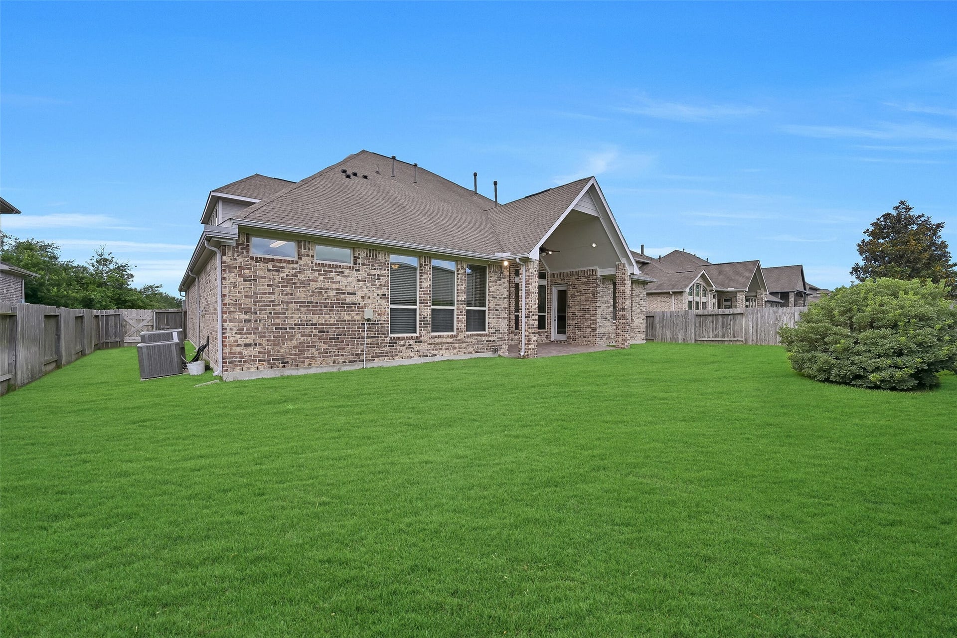 1321 Summer Field Lane, Friendswood, TX 77546 From this angle, the impressive depth and width of the backyard are fully appreciated. The expansive lawn provides room for pets, play equipment, or a custom pool while still leaving plenty of yard to enjoy. The home's attractive brick exterior, large windows, and covered patio create an inviting backdrop for outdoor living.