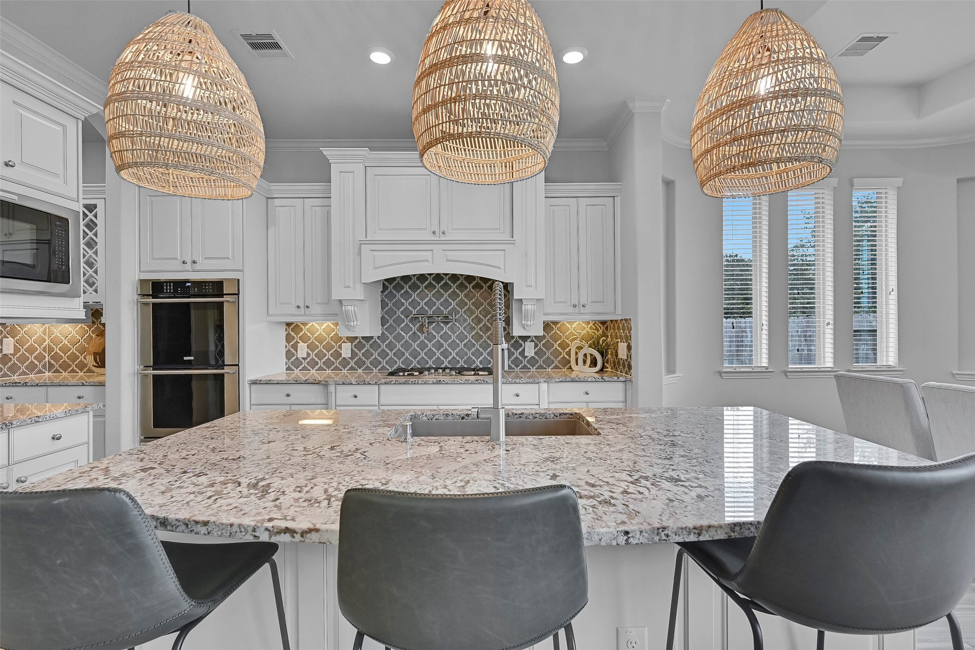 1321 Summer Field Lane, Friendswood, TX 77546 An oversized granite island anchors the kitchen and features a huge single-basin composite sink with a commercial-grade pull-down faucet. Beyond, you'll find custom cabinetry, dual Electrolux convection ovens, and a striking arabesque tile backsplash that extends throughout the space.