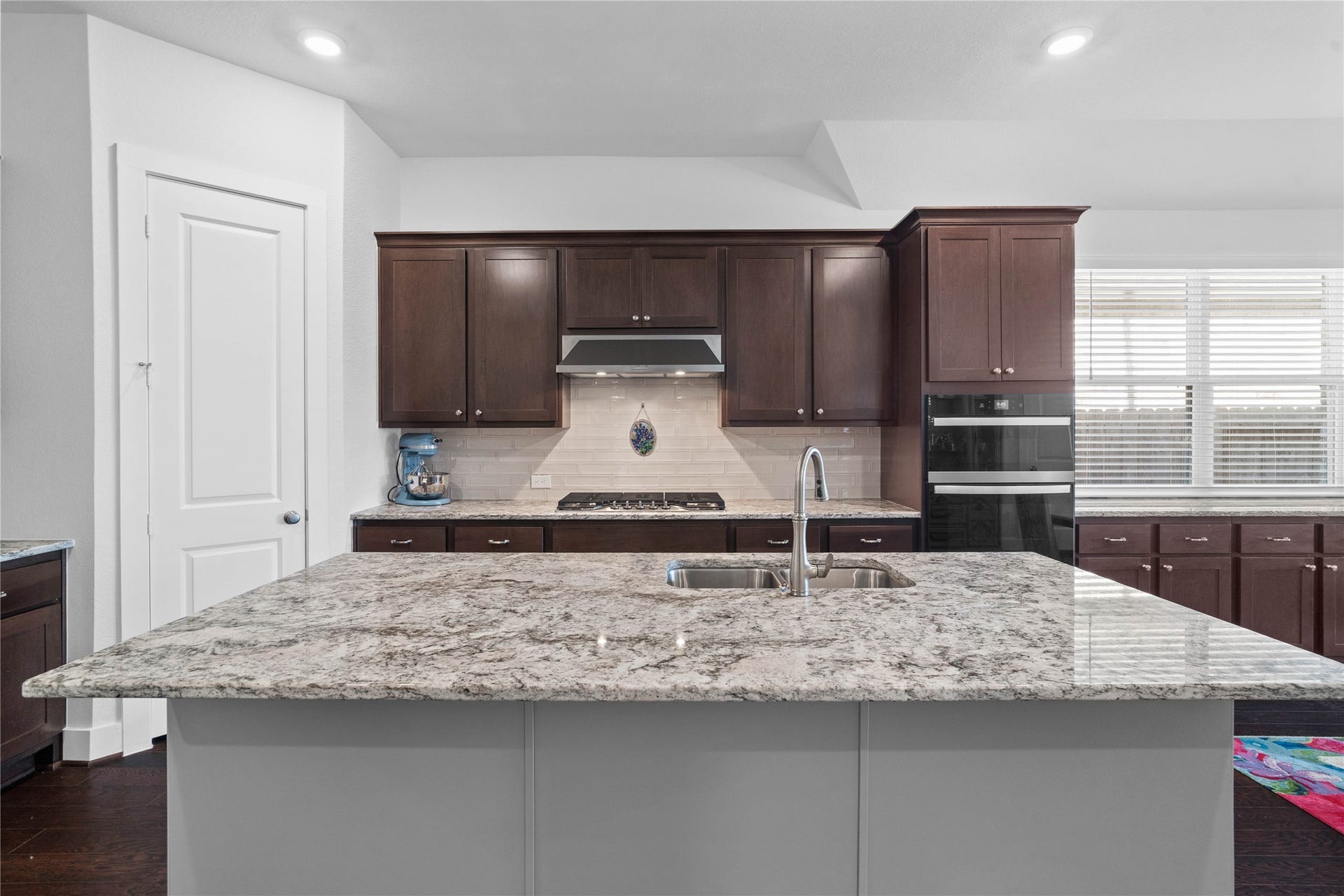 The expansive kitchen island offers plenty of space for family gathering and entertaining, featuring a beautiful granite countertop that extends into an additional breakfast bar perfect for casual morning seating.