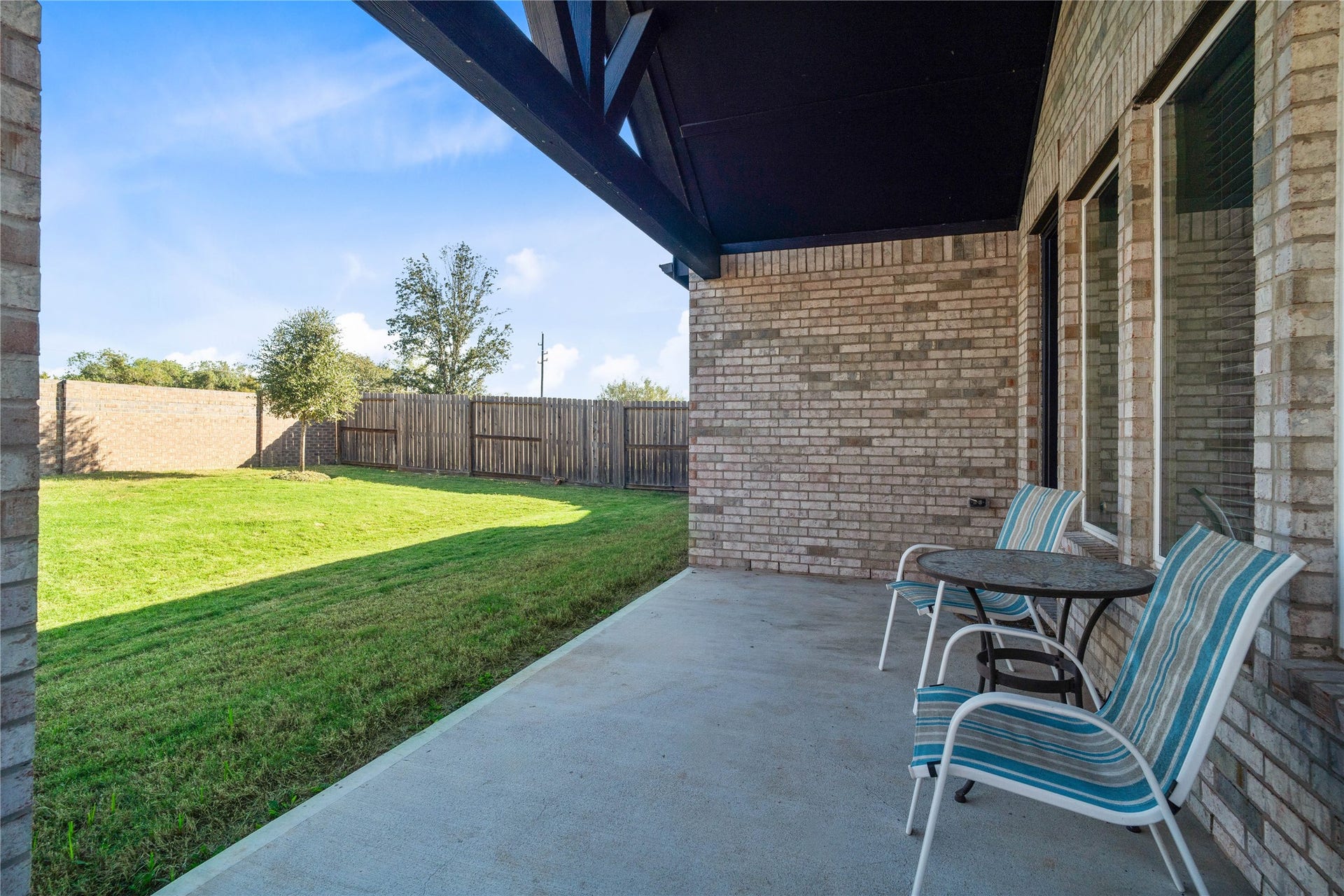Step outside to this spacious covered patio featuring a dramatic vaulted cedar gable roofline, providing the perfect shaded retreat for outdoor dining, relaxing, and looking out over the expansive backyard.