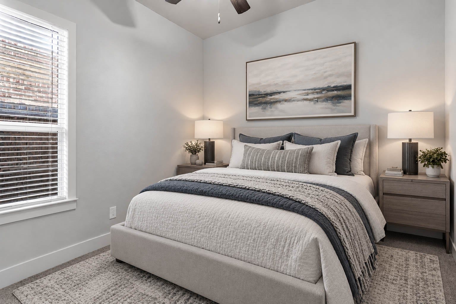 Situated on the opposite side of the home for optimal privacy, this bright secondary bedroom offers soft plush carpeting, neutral paint tones, a ceiling fan, and a large window fitted with blinds. *Virtually Staged