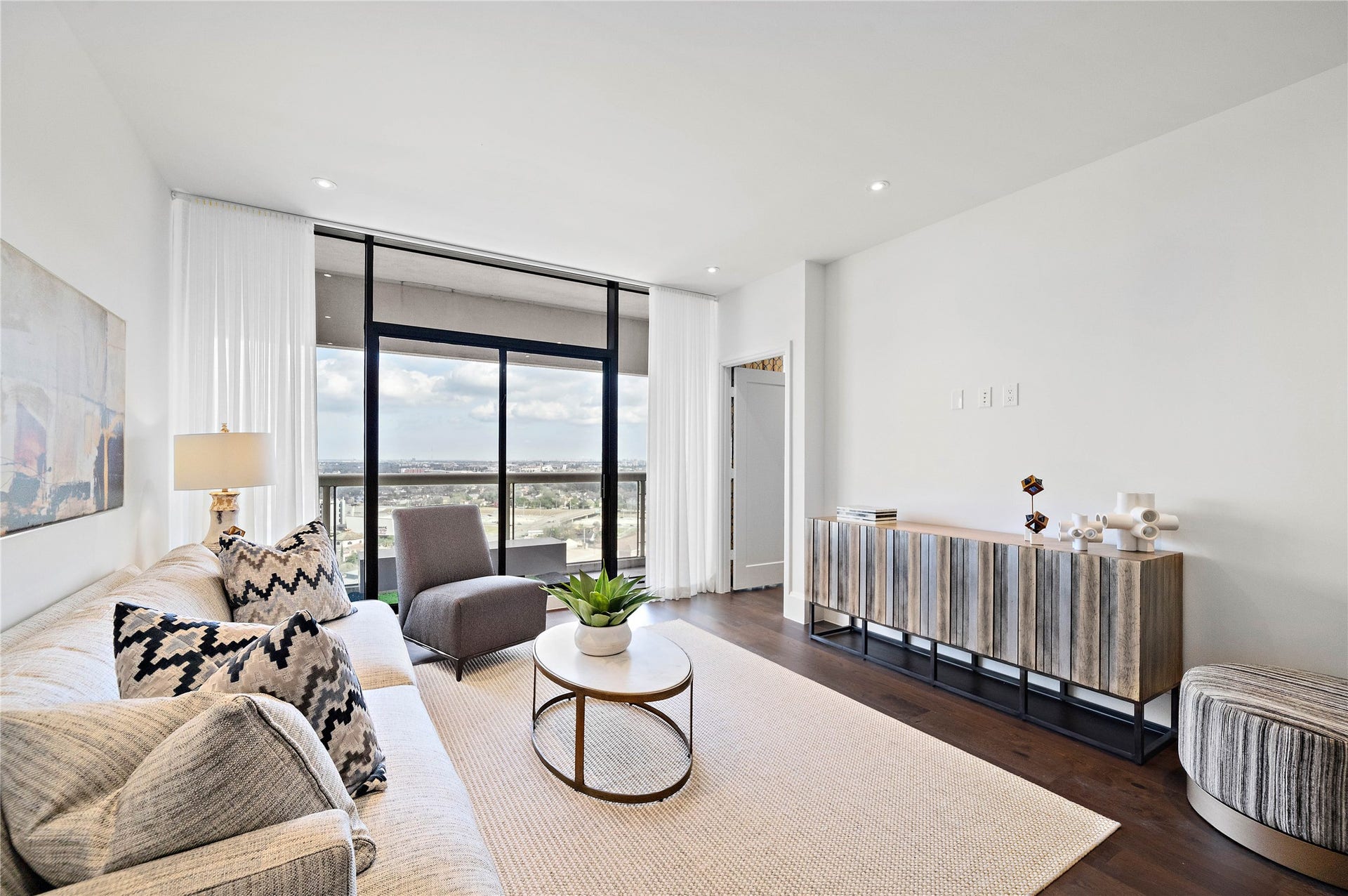 1701 Hermann Drive, #25A, Houston, TX 77004 The main living area is drenched in natural light that pours through a wall of glass and sliding door onto balcony.