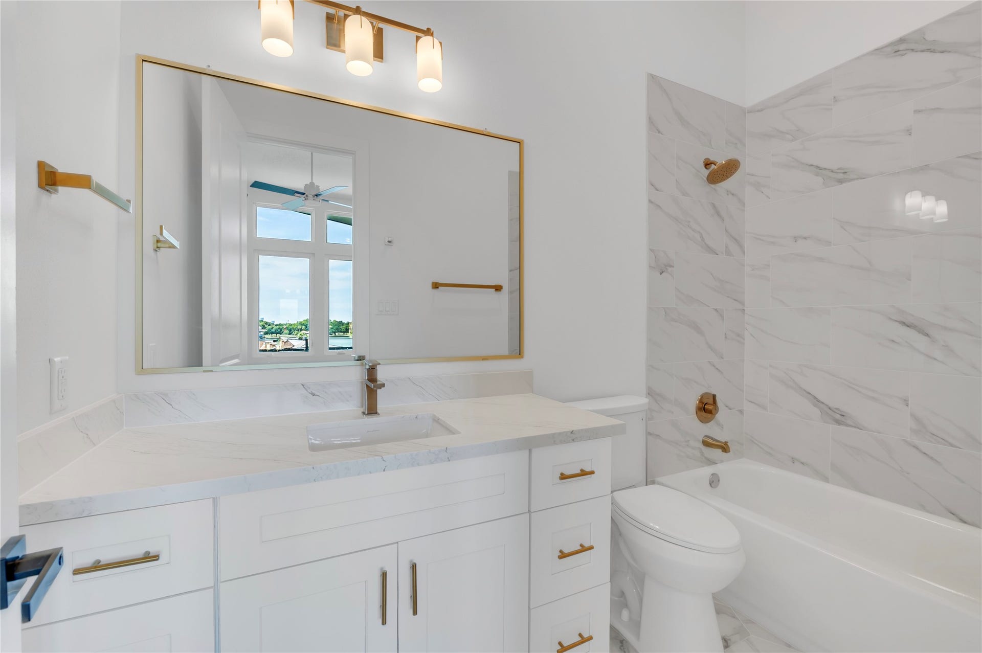 119 Kirby Road, #5304, Taylor Lake Village, TX 77586 Elegant bathroom featuring a luxurious marble countertop and backsplash, complemented by modern gold fixtures and a spacious bathtub.