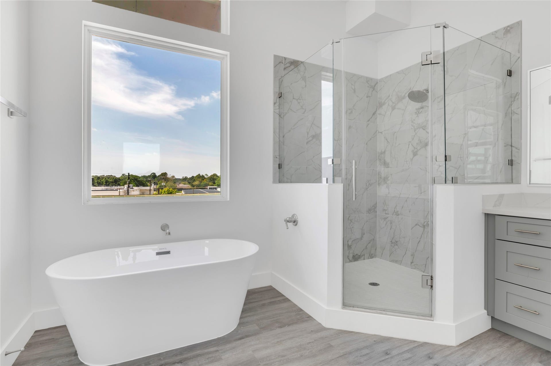 119 Kirby Road, #5304, Taylor Lake Village, TX 77586 Elegant bathroom featuring a luxurious freestanding tub, spacious glass-enclosed shower with marble tile, and a bright window offering serene views.