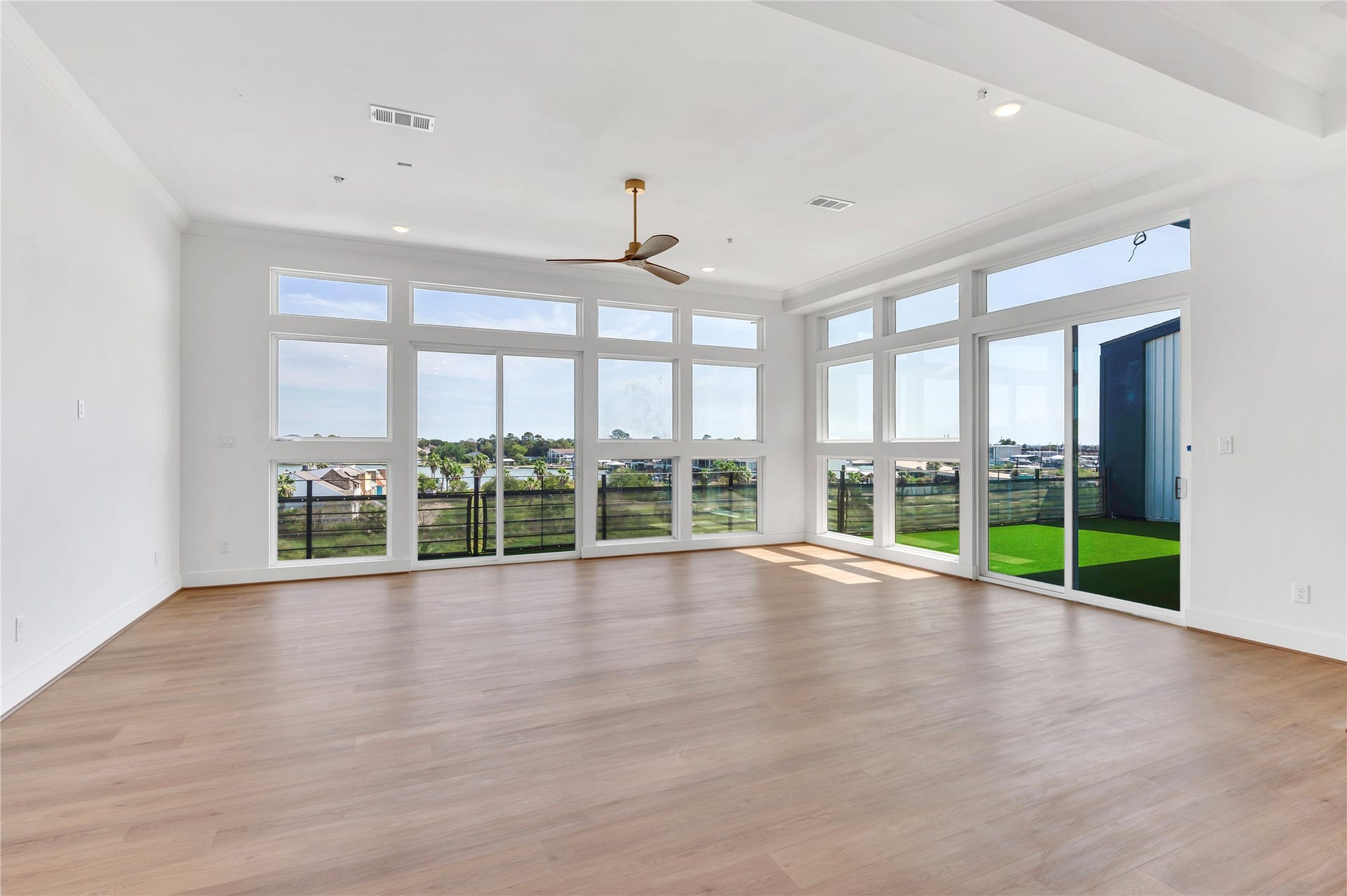 119 Kirby Road, #5304, Taylor Lake Village, TX 77586 Expansive living area with floor-to-ceiling windows, abundant natural light, and scenic views, complemented by sleek wood flooring and a modern ceiling fan.