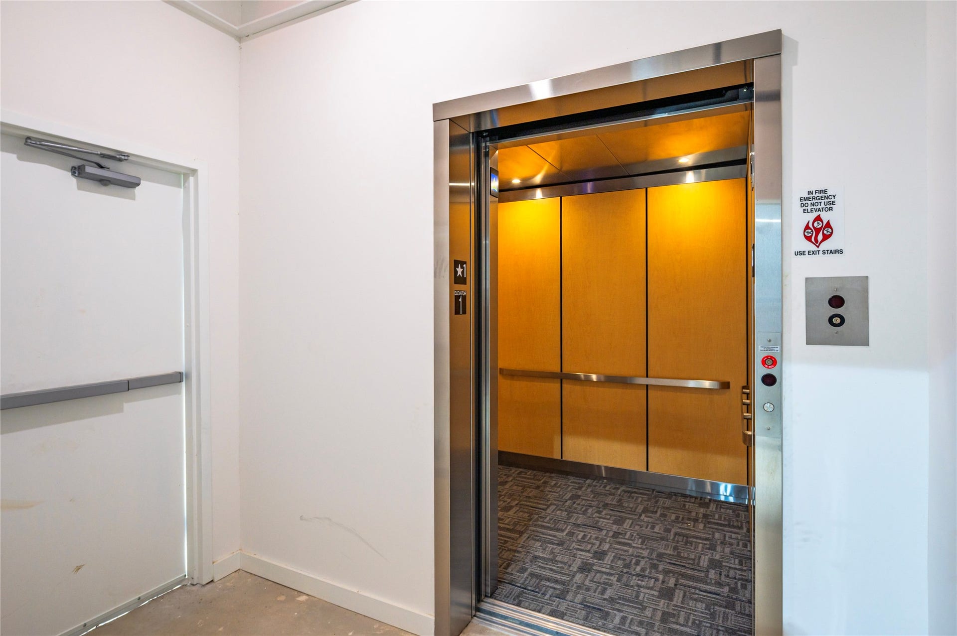119 Kirby Road, #5304, Taylor Lake Village, TX 77586 Modern elevator with sleek wood paneling and carpeted flooring, providing convenient access within the building.