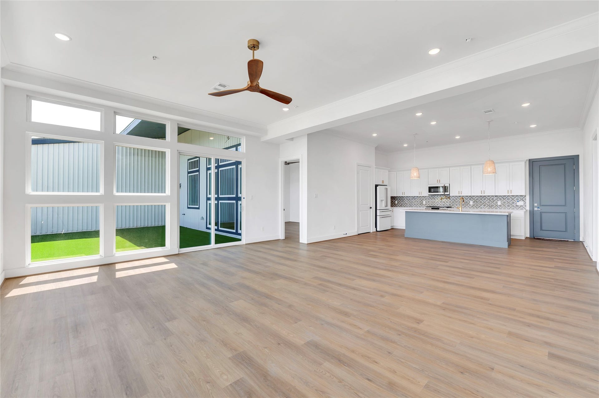 119 Kirby Road, #5304, Taylor Lake Village, TX 77586 Bright and spacious open-concept living area with large windows, elegant wood flooring, and a modern kitchen featuring sleek appliances and a stylish backsplash.