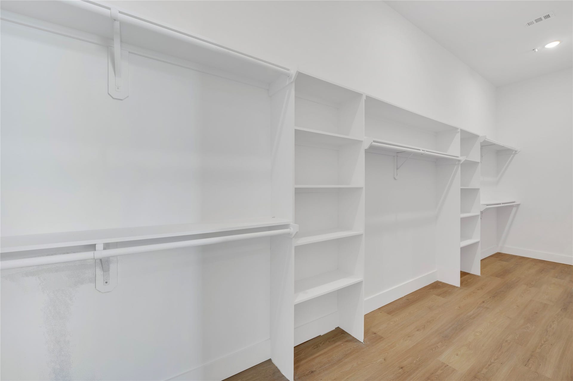 119 Kirby Road, #5304, Taylor Lake Village, TX 77586 Spacious walk-in closet featuring ample shelving and hanging space, complemented by warm wood flooring and bright lighting.