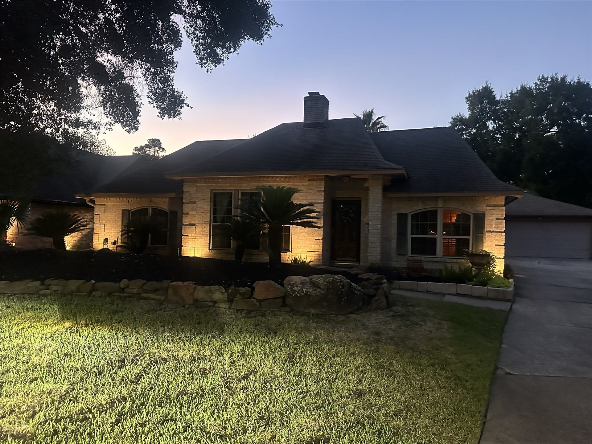 Beautifully illuminated landscaping and warm exterior lighting create a welcoming glow, showcasing this home's charm from the moment you arrive.
