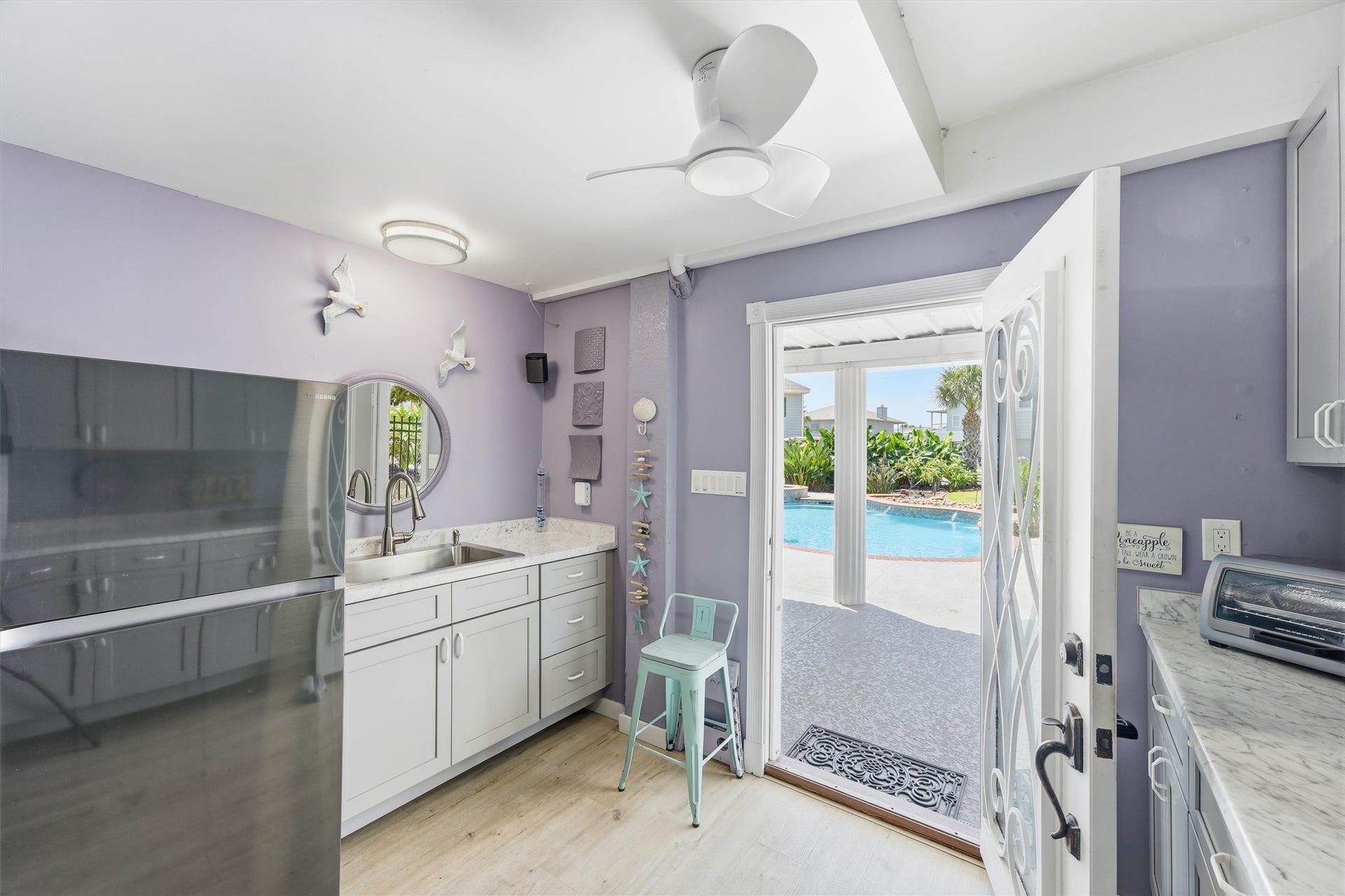 Pool house offers a convenient kitchenette with direct access to the pool and outdoor entertaining areas, creating the perfect setup for poolside drinks, snacks, and gatherings.