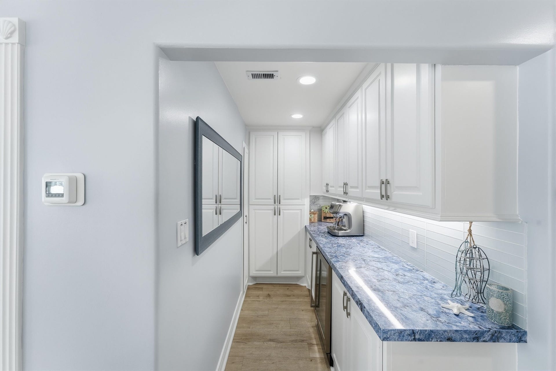 Additional prep and storage area offers extensive cabinetry, counter space, under-cabinet lighting, and a beverage refrigerator.