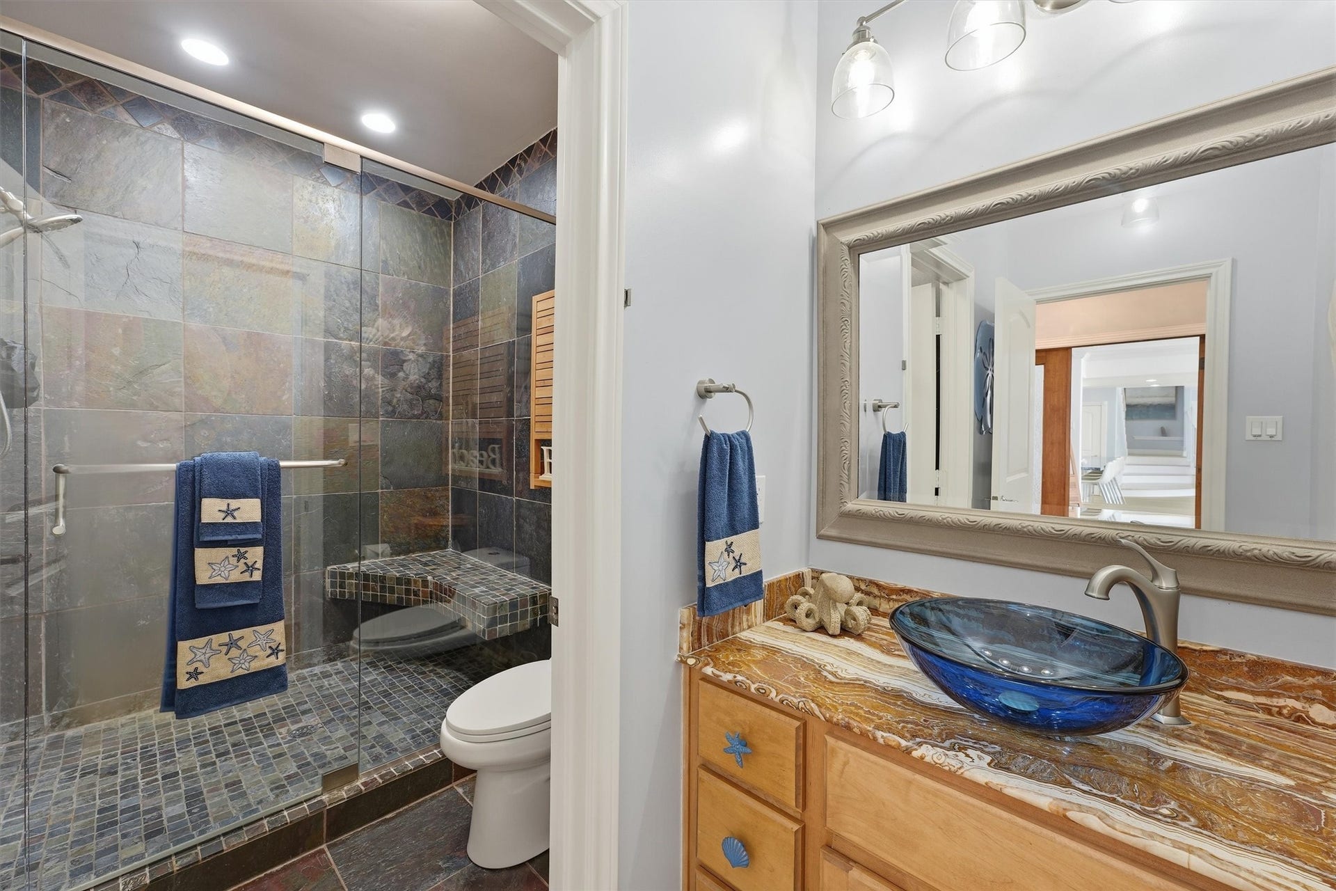 Full guest bath featuring a glass-enclosed walk-in shower and distinctive coastal finishes.
