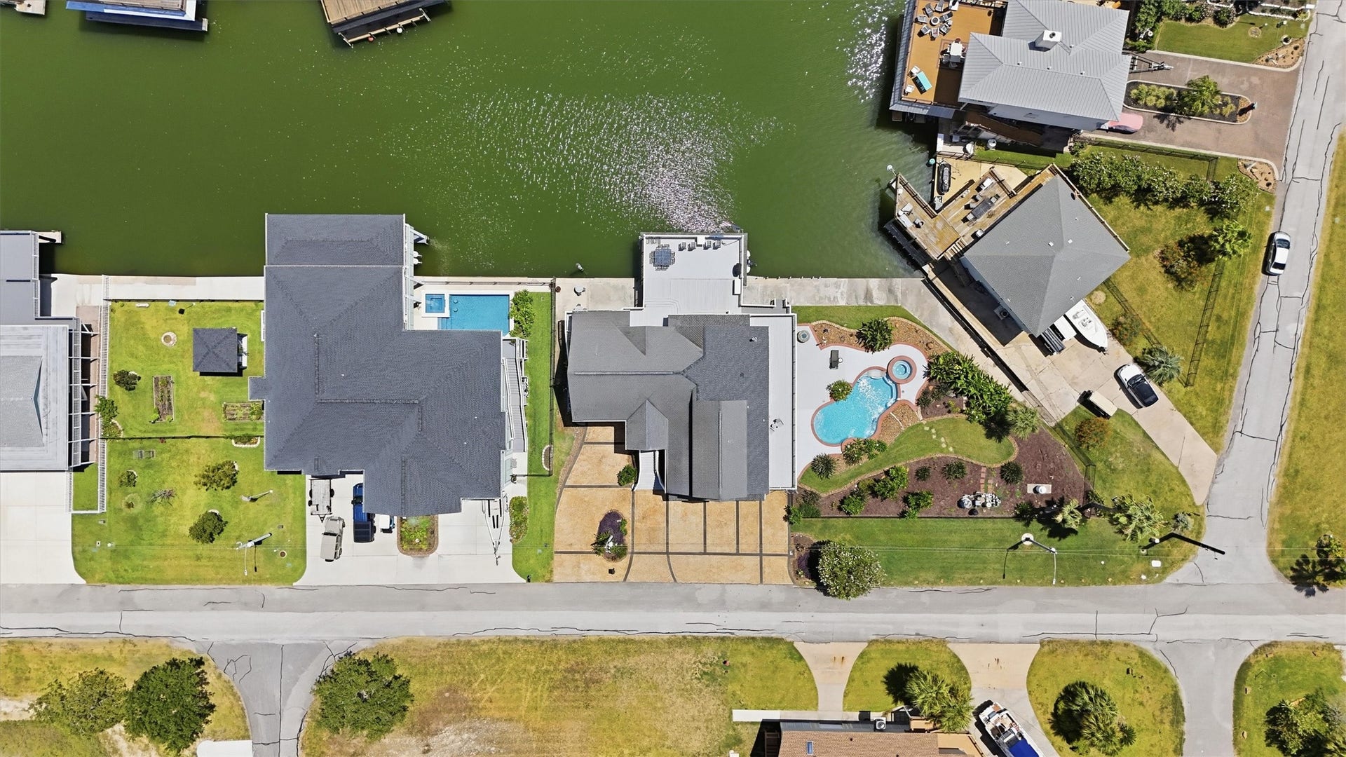 This view showcases the homes generous corner lot, private pool and spa, landscaped outdoor spaces, and direct canal frontage, all designed around the Tiki Island lifestyle.