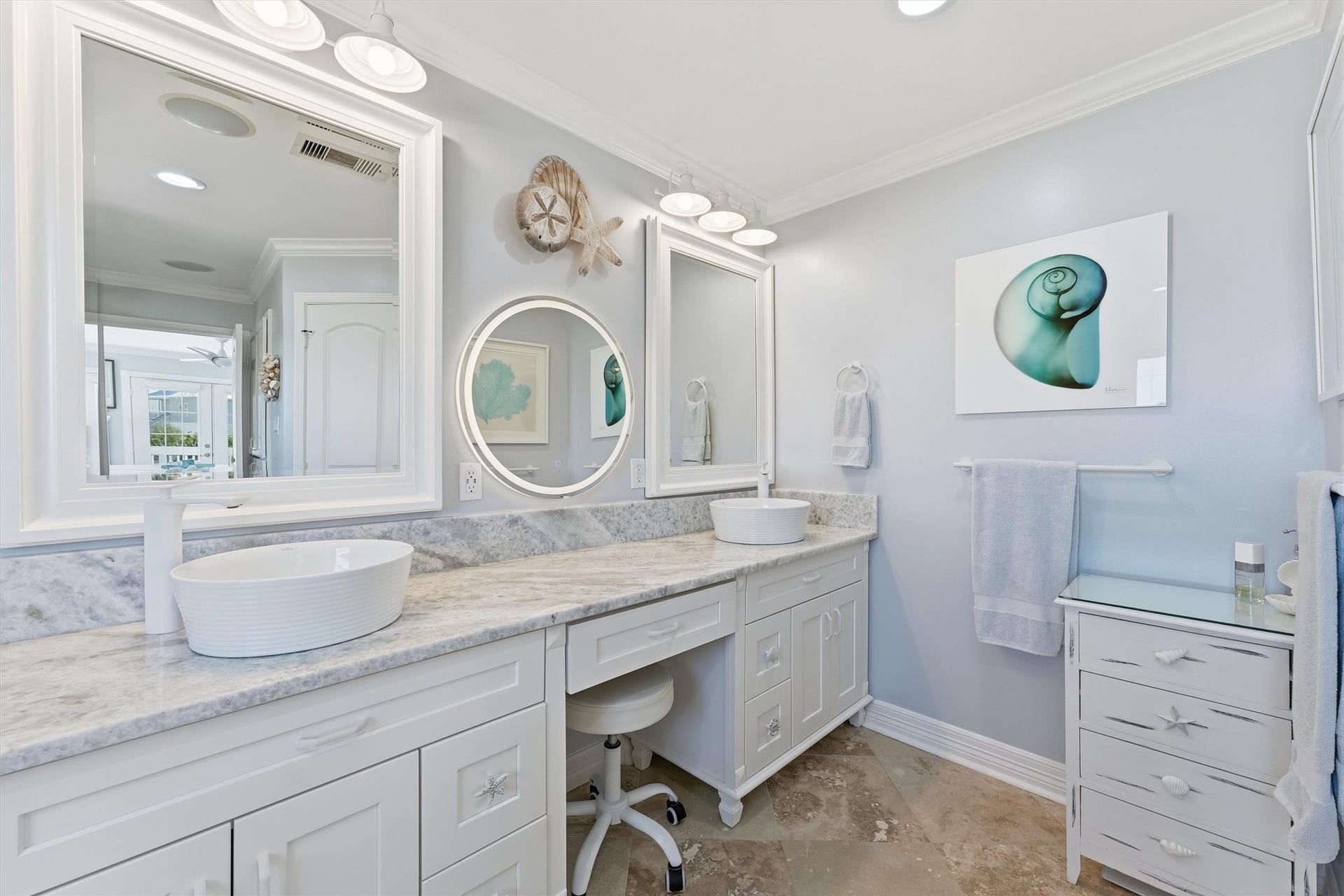 Primary bath features an extended vanity with dual vessel sinks, generous storage, and dedicated vanity seating.