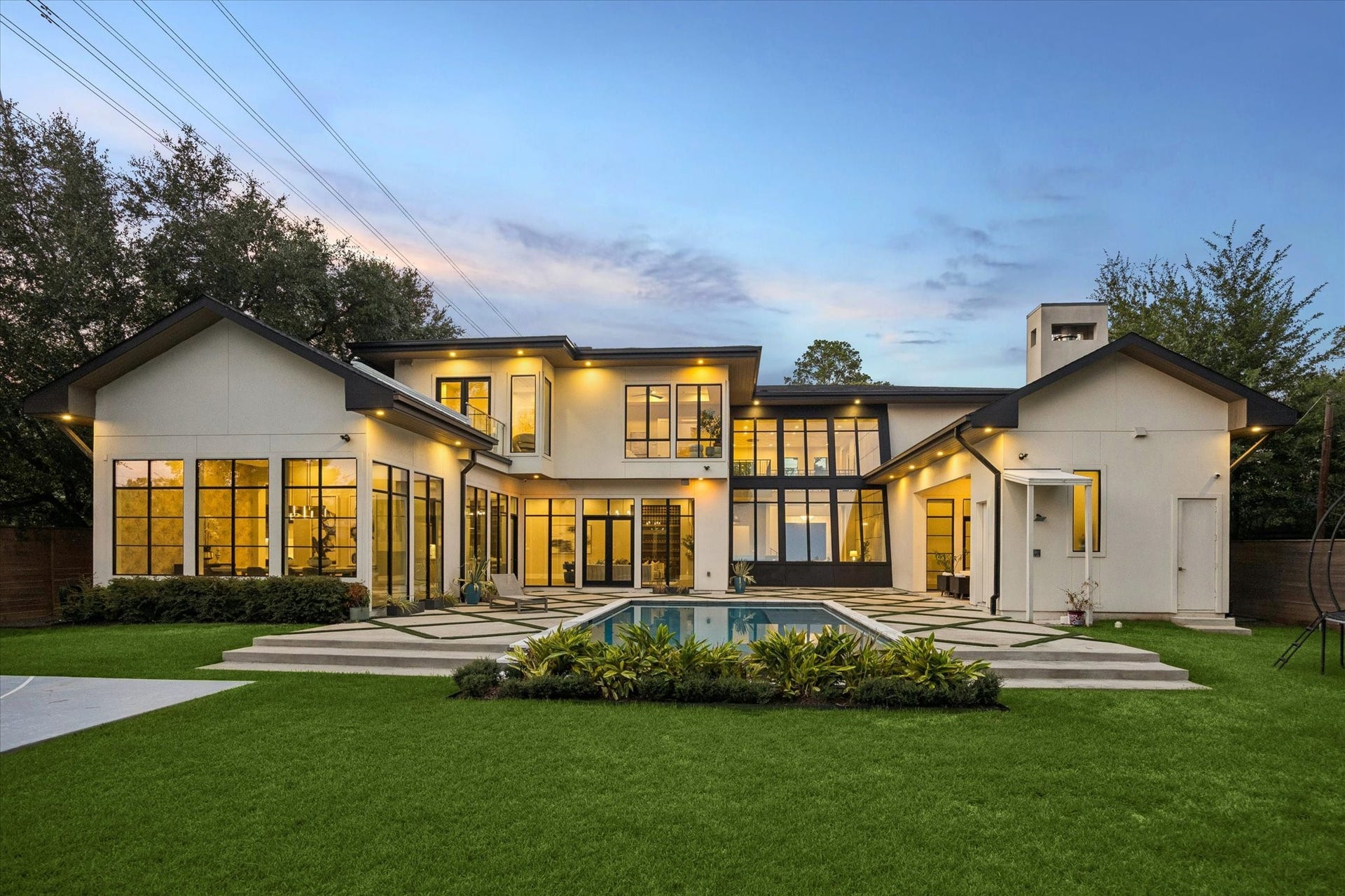 10943 Britoak Lane, Houston, TX 77079 Resort-style backyard featuring a sparkling pool, covered outdoor kitchen and living area, lush landscaping, and expansive patio space ideal for entertaining.