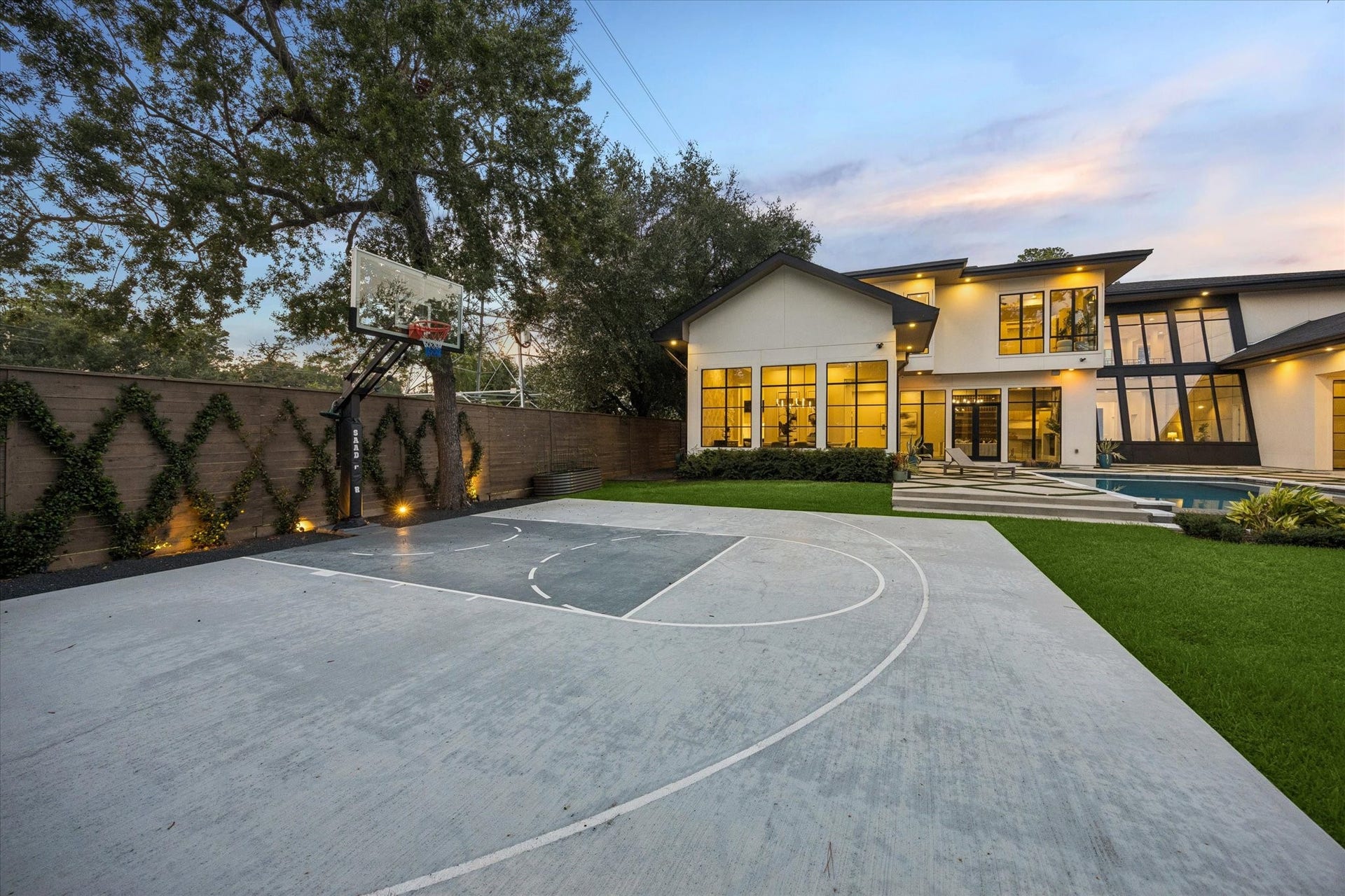 10943 Britoak Lane, Houston, TX 77079 Private backyard basketball court surrounded by mature trees and lush landscaping, offering an exceptional space for recreation and outdoor enjoyment.