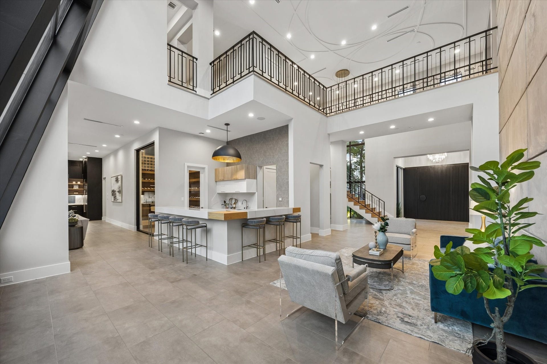 10943 Britoak Lane, Houston, TX 77079 Impressive open-concept living space with soaring ceilings, a striking staircase, contemporary finishes, and a sleek bar designed for effortless entertaining.