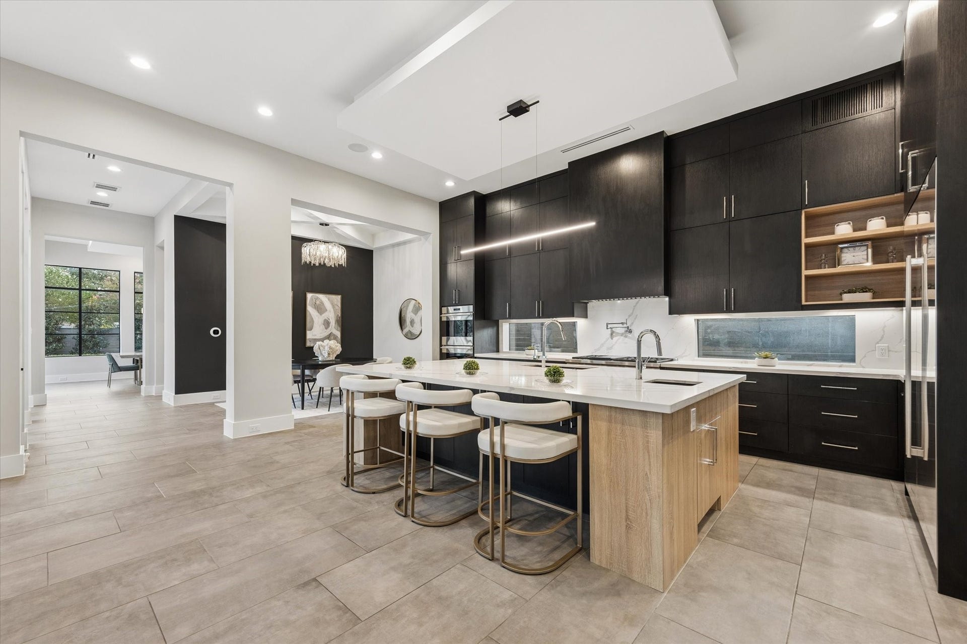 10943 Britoak Lane, Houston, TX 77079 A stunning modern kitchen with sleek dark cabinetry, a spacious island, and high-end appliances. The open layout flows seamlessly into a bright dining area, perfect for entertaining.