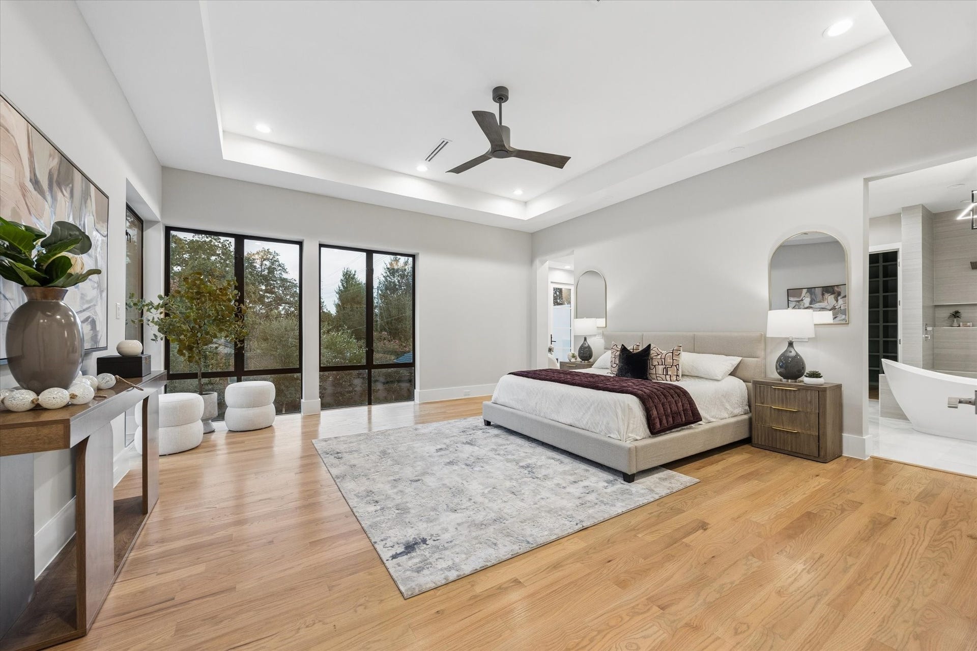 10943 Britoak Lane, Houston, TX 77079 Spacious primary suite featuring a tray ceiling, expansive windows, warm hardwood floors.
