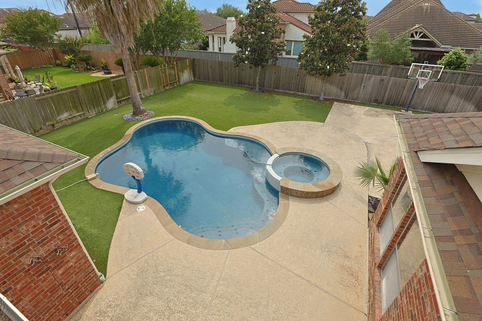 Backyard is an oasis with pool, hot tub, basketball court and low maintenance artificial turf.