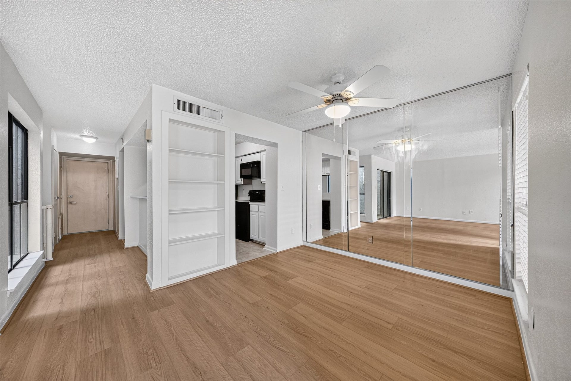 Open dining area with built-in shelving, mirrored accent wall, and convenient access to the kitchen.