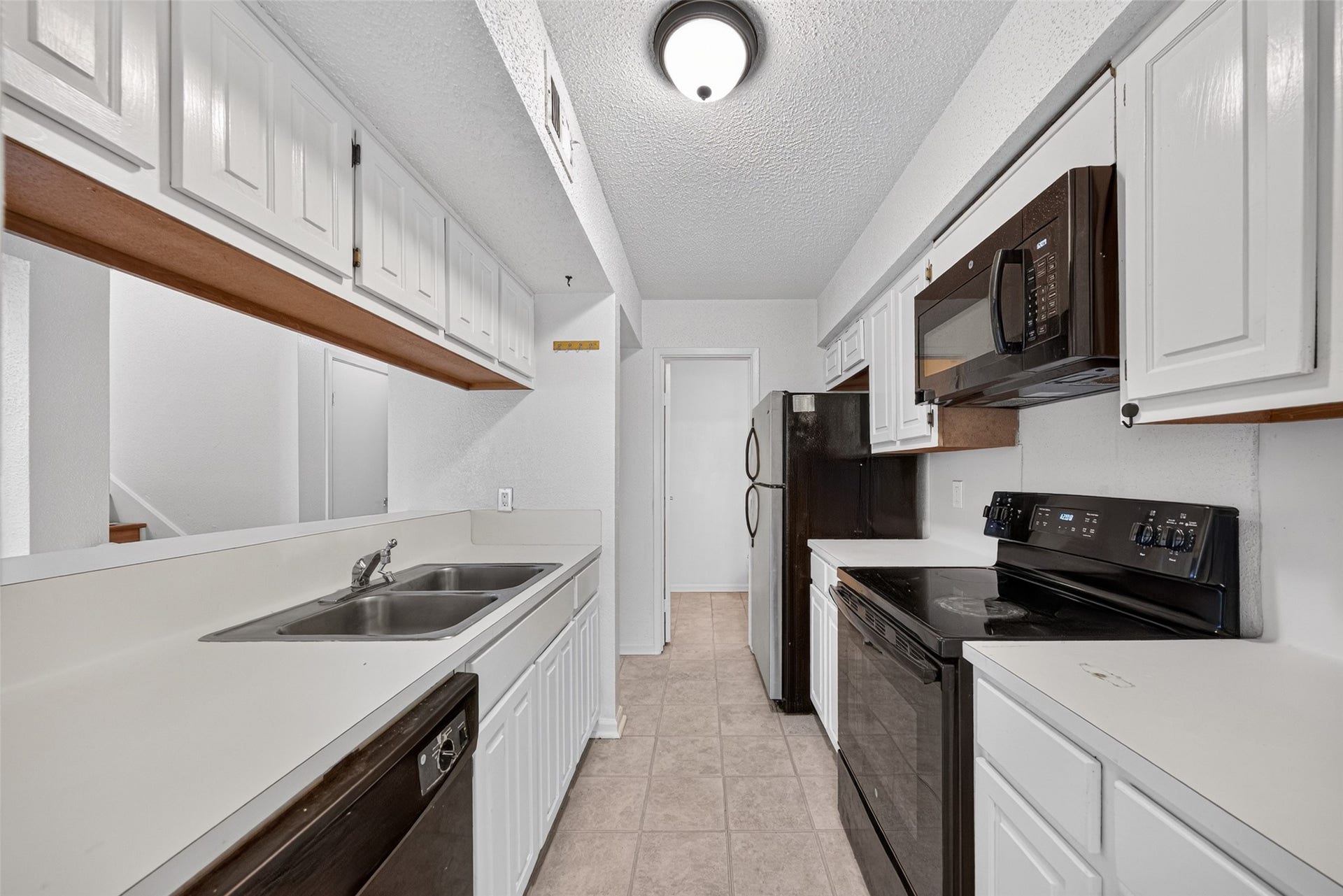 Galley-style kitchen with white cabinetry and breakfast bar