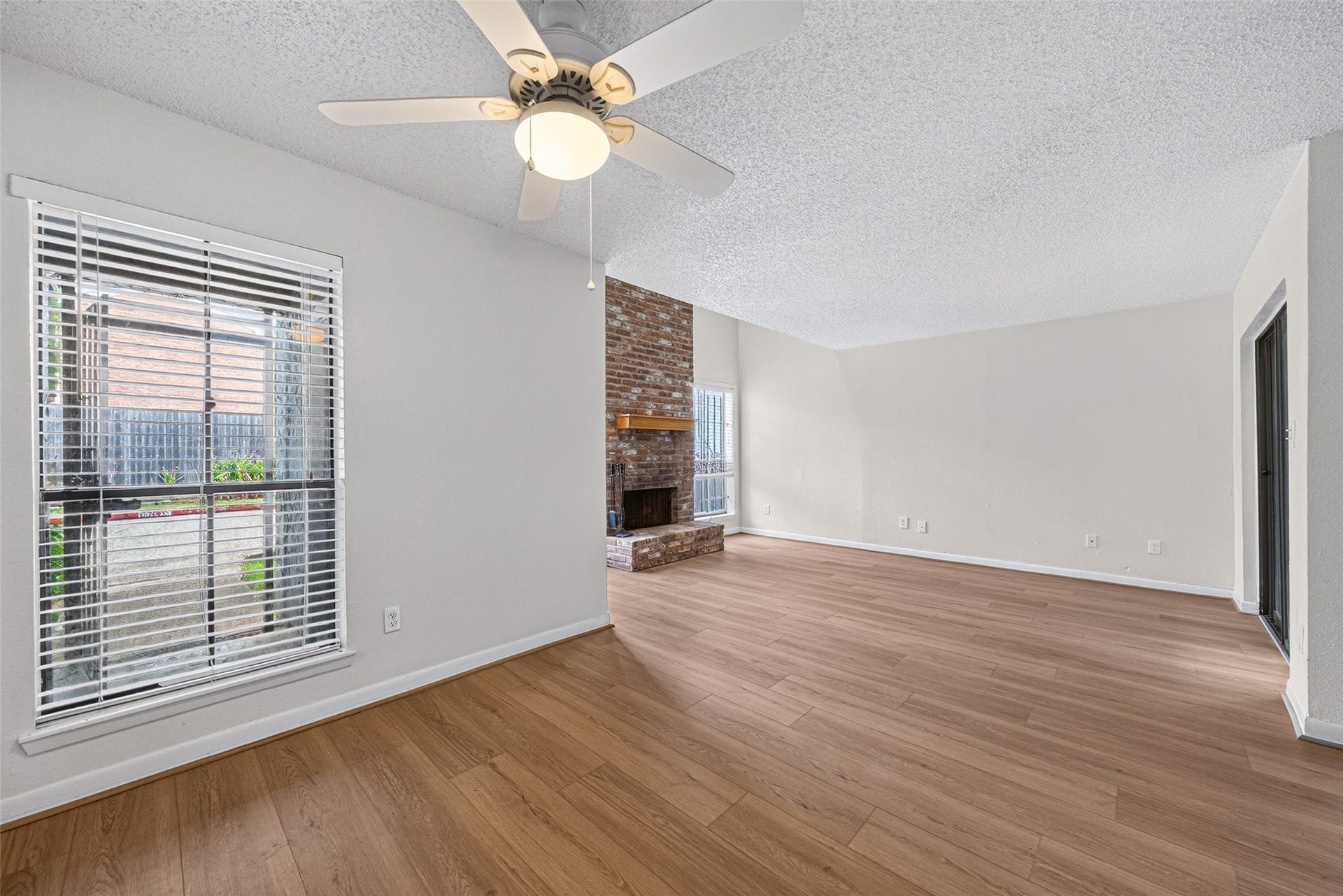 Open-concept living and dining areas with new vinyl flooring, abundant natural light, and a brick fireplace.
