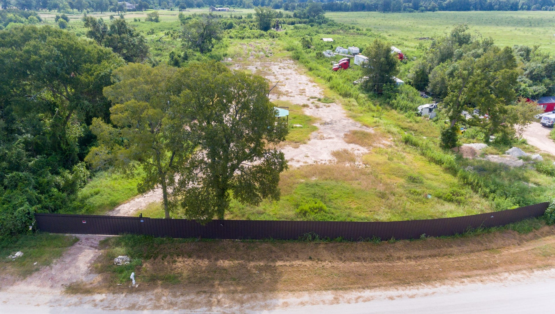 This photo shows a spacious, partially fenced plot of land with a mix of open grassy areas and mature trees. The property offers a secluded feel with plenty of greenery and potential for development or personal use, ideal for those seeking privacy and natural surroundings.