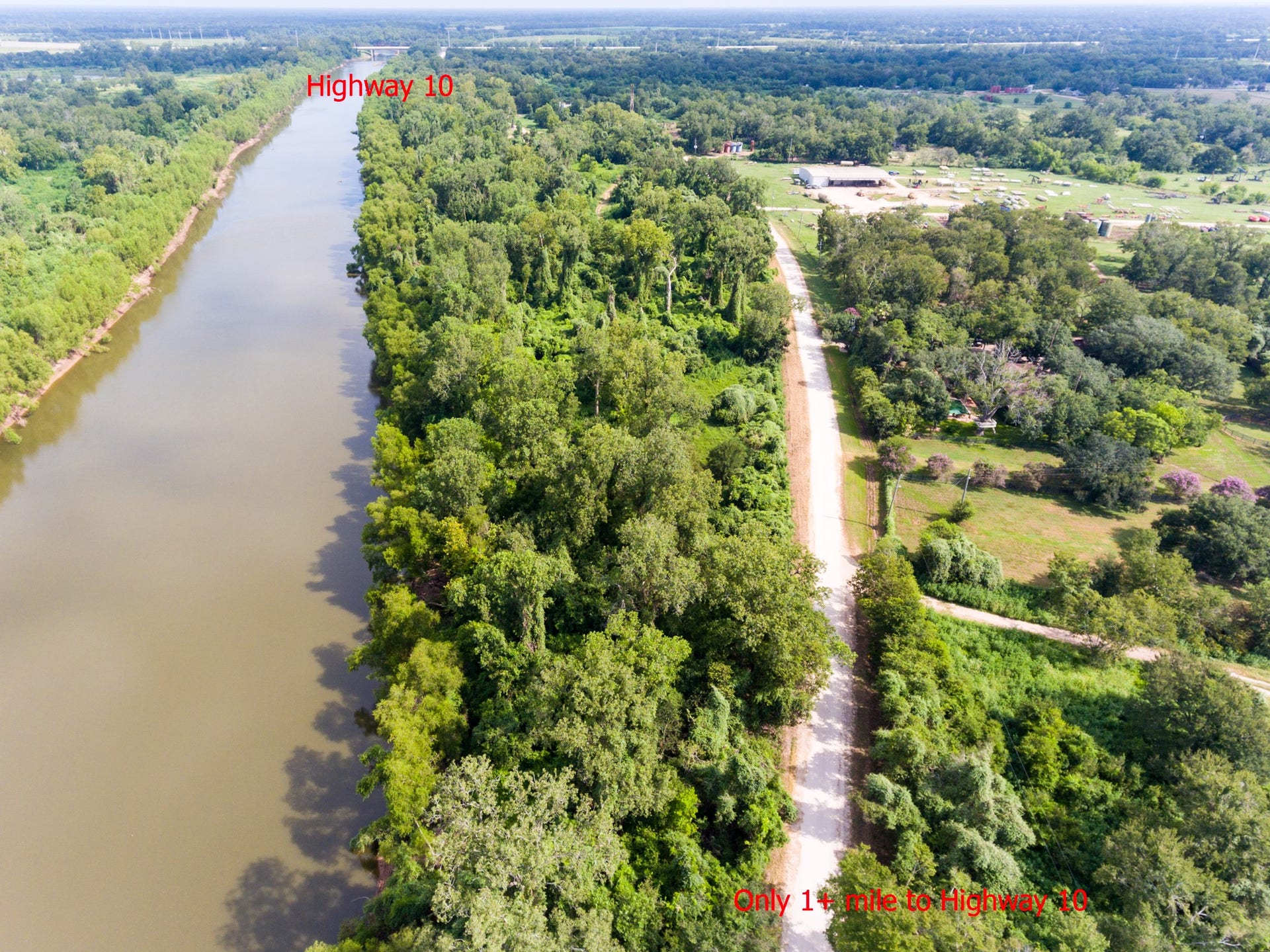 Scenic aerial view showcasing a lush, wooded area with a river running alongside. A nearby road leads through the greenery, connecting to Highway 10 just over a mile away, offering both tranquility and accessibility.