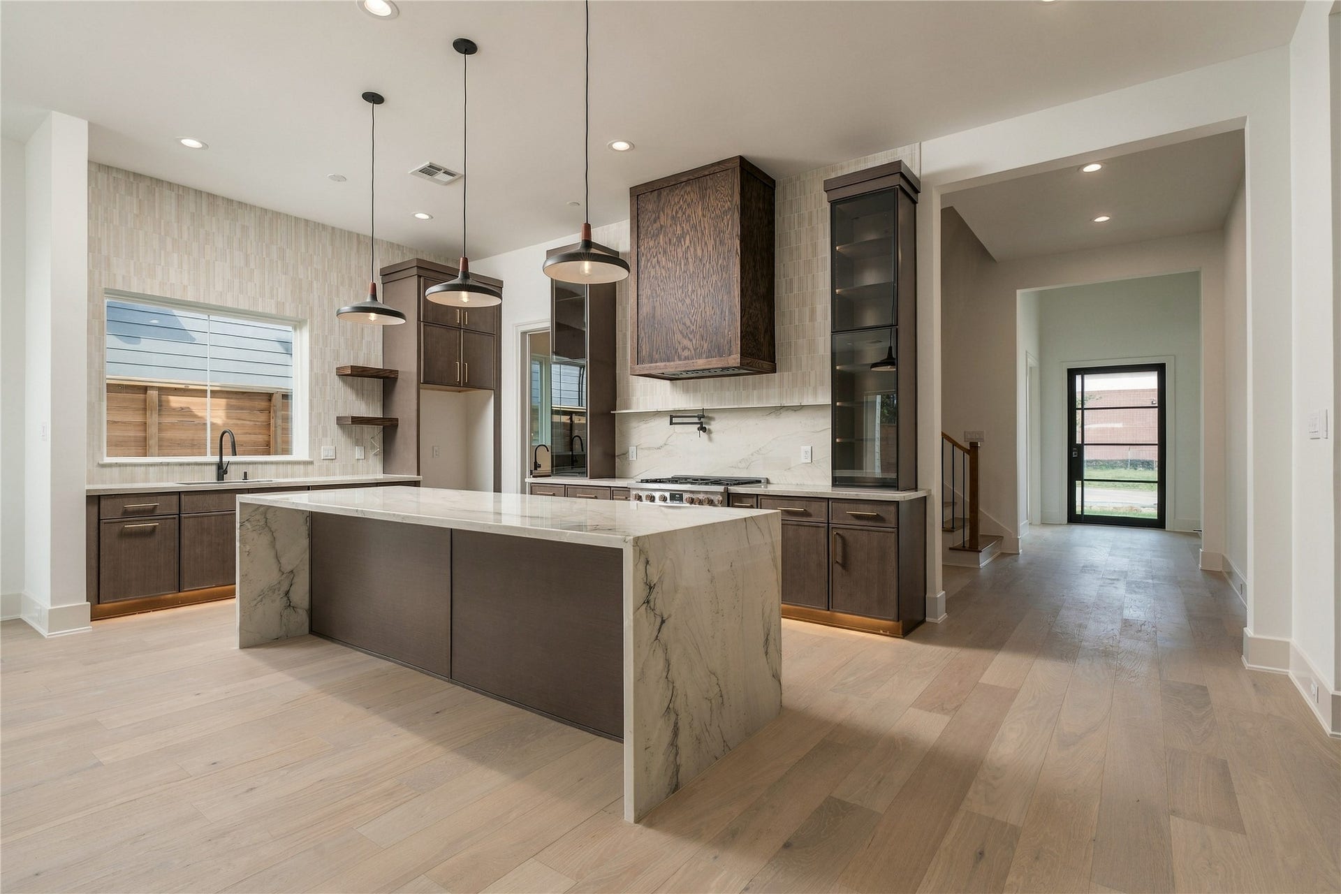2107 McKean Drive, Houston, TX 77080 The kitchen makes an immediate statement with imported Mount Blanc Quartzite, custom cabinetry, and a dramatic oversized island, creating a natural centerpiece for both everyday living and entertaining.