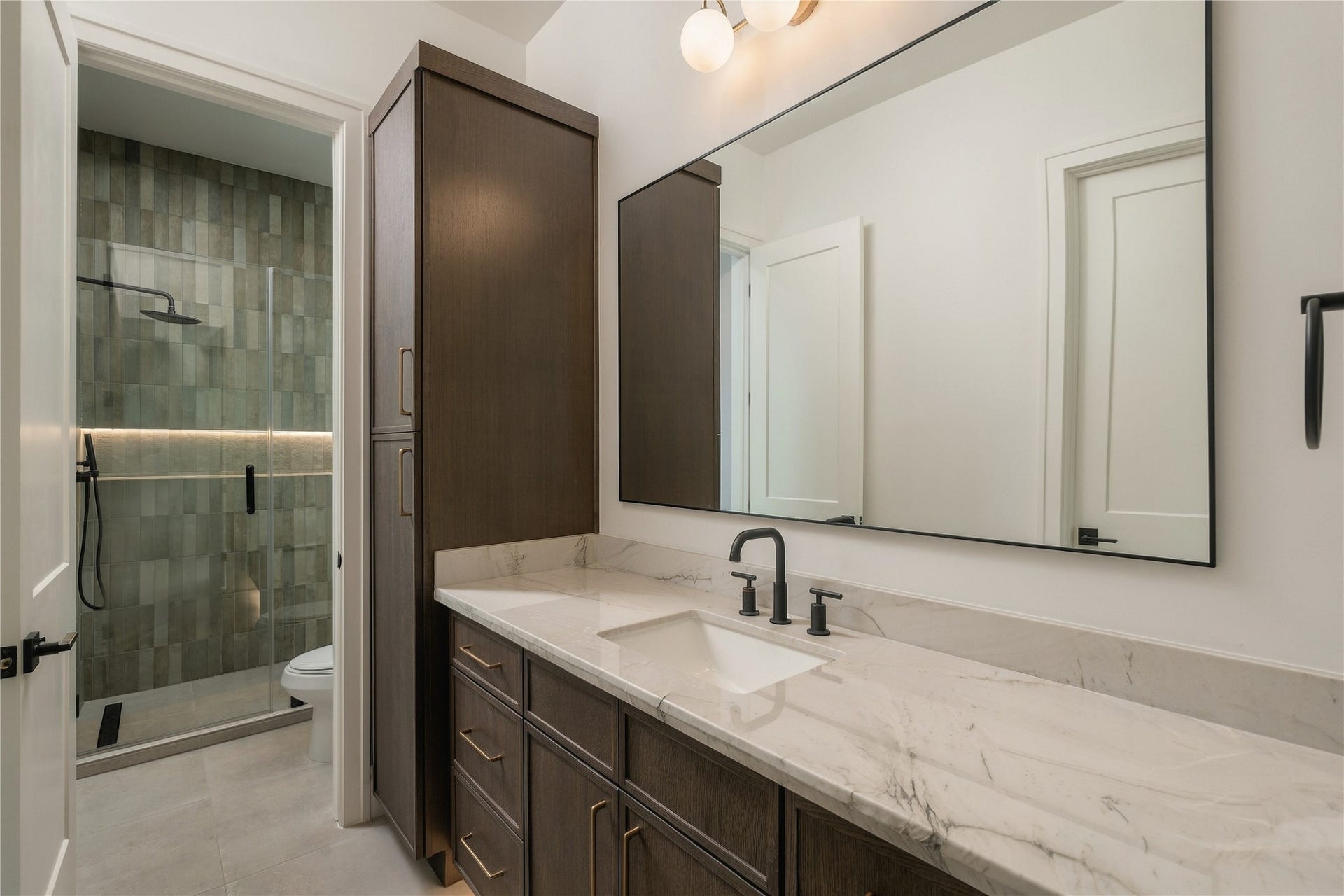 2107 McKean Drive, Houston, TX 77080 The secondary bath is finished with Mount Blanc Quartzite countertops, full-height designer tile, and a frameless glass shower, bringing the same level of finish found throughout the home into the guest accommodations.