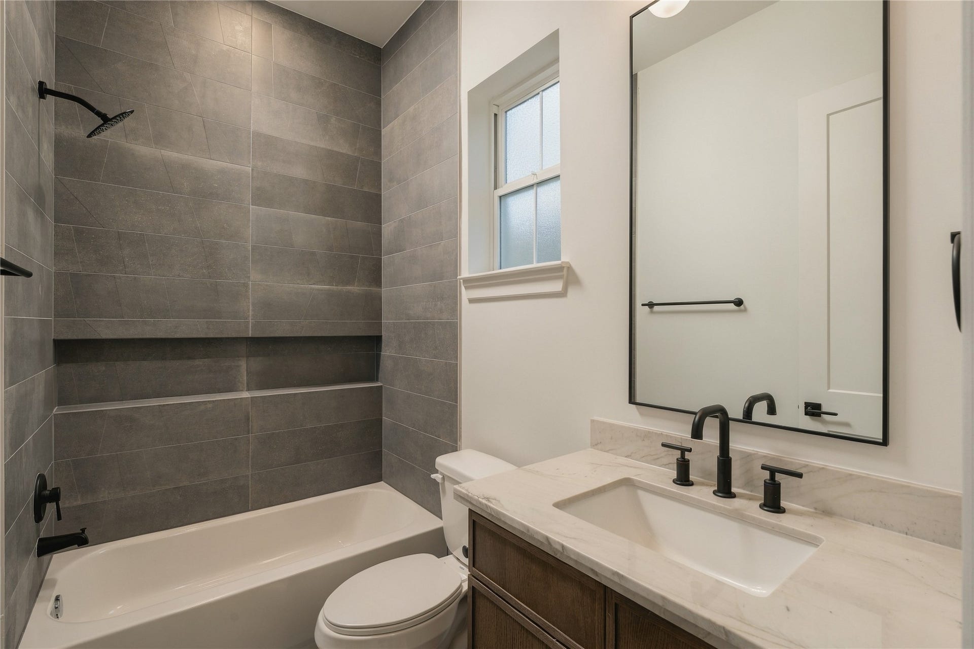 2107 McKean Drive, Houston, TX 77080 A well-appointed secondary bath features a frameless glass shower, full-height designer tile, and a shower niche, continuing the homes attention to detail across every ensuite.