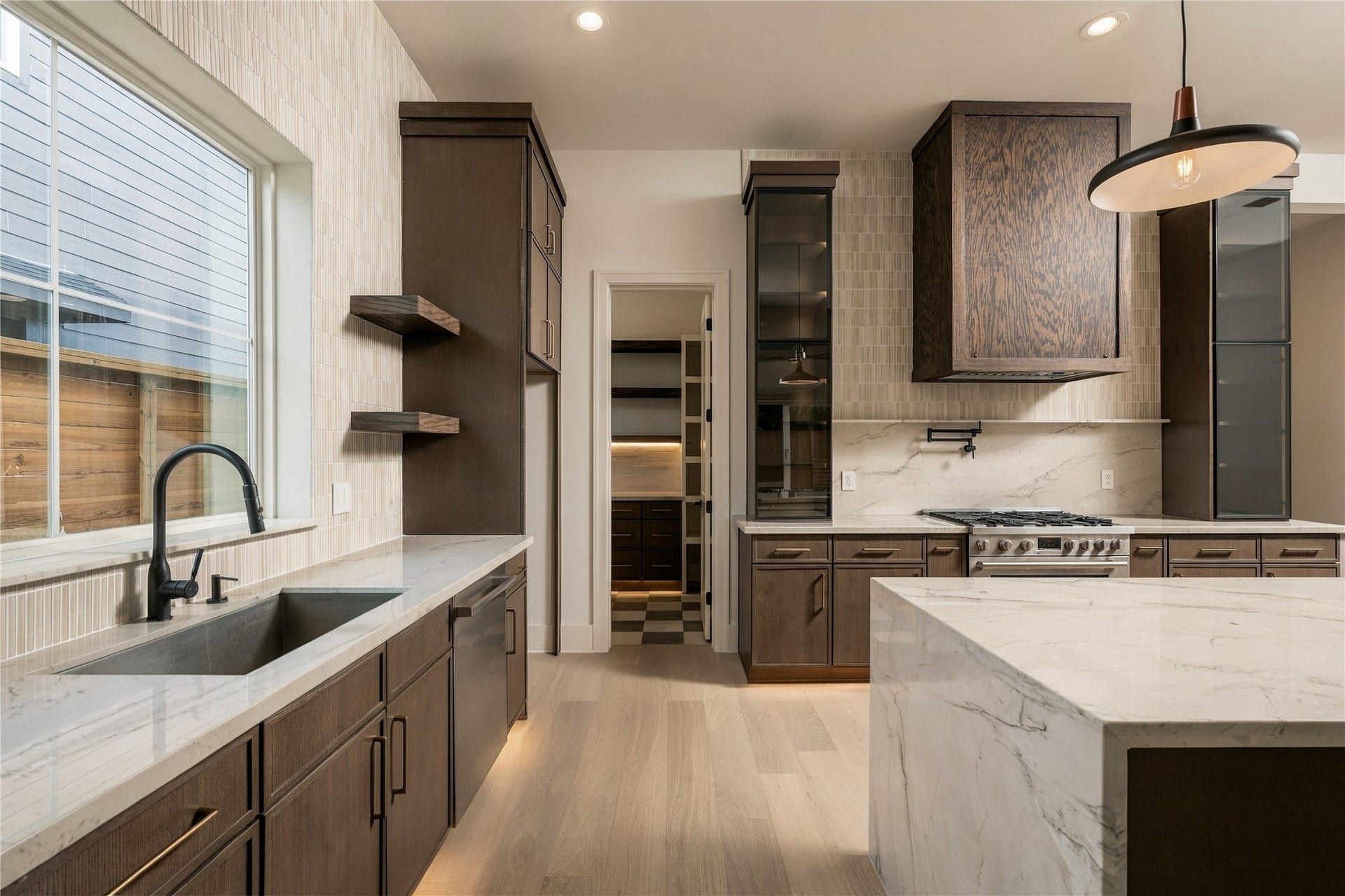 2107 McKean Drive, Houston, TX 77080 A closer view reveals the kitchens layered craftsmanship, where custom white oak details, glass-front cabinetry, and integrated LED lighting bring warmth and dimension to the space.